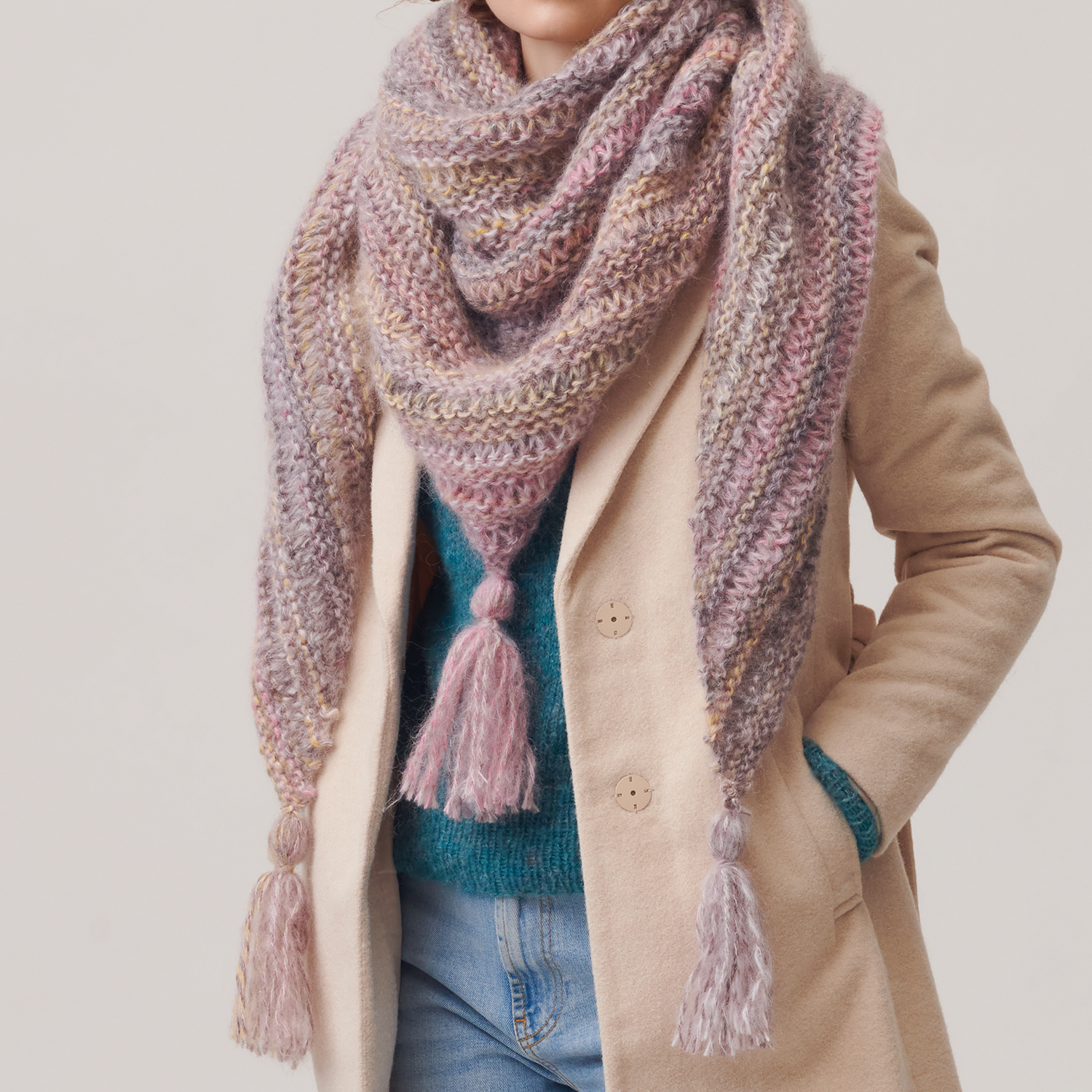 Strickanleitung Dreieckstuch aus Creative Mohair Melange: Frau trägt pastellfarbenes, gestricktes Tuch mit Fransen über einem Mantel.