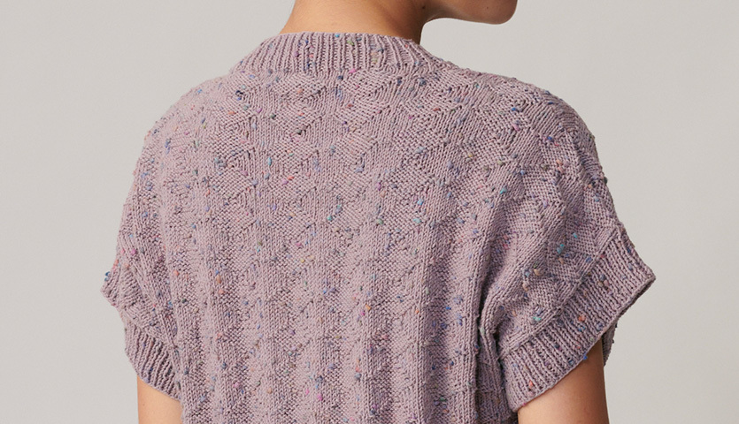 Strickanleitung Top aus Fashion Cotton Neps dk: Rückansicht eines lila gestrickten Tops mit kurzen Ärmeln und feinem Muster.