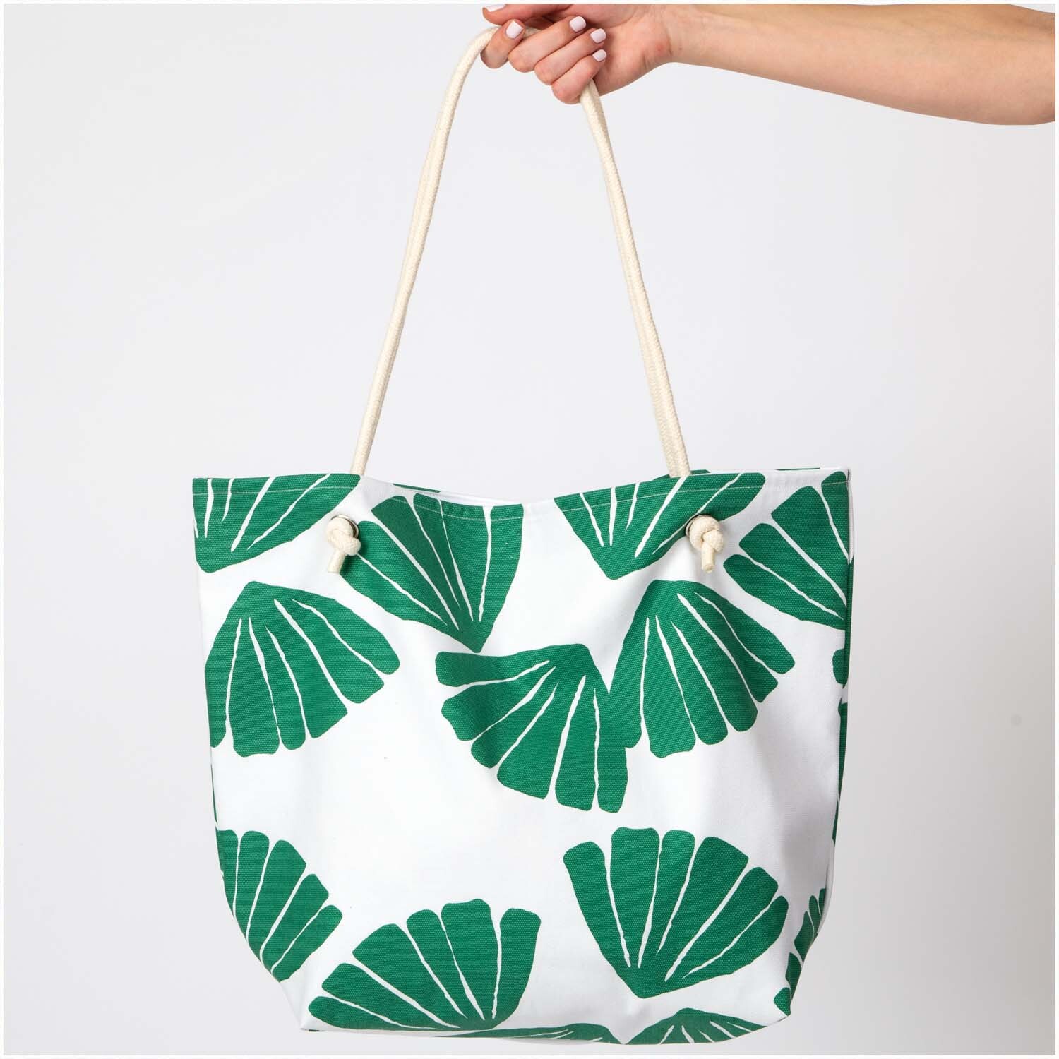 Druckstoff Canvas Aloha Blätter 140cm: Große Tasche mit grünem Blattmuster, gehalten von einer Hand. Ideal für den Sommer.
