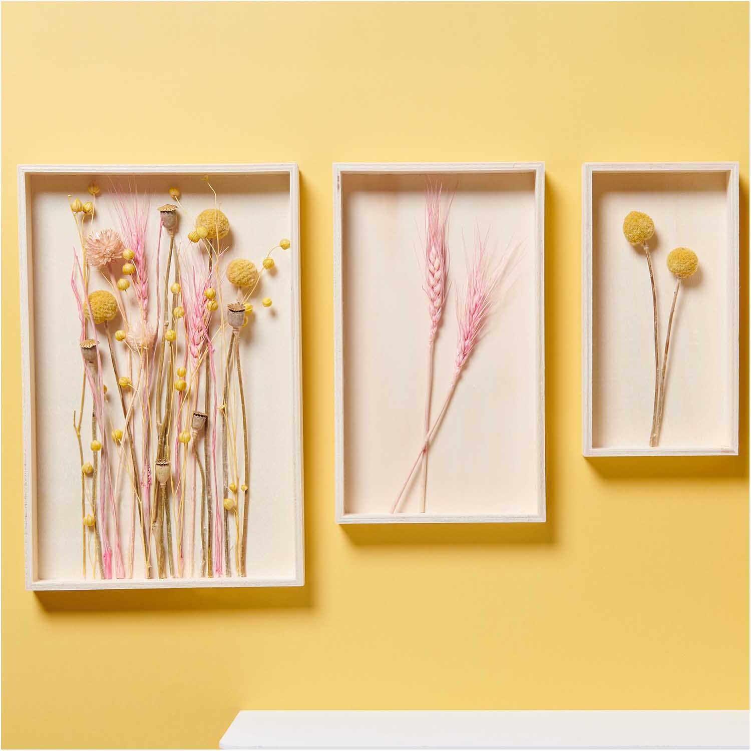 Getrockneter Flachs gelb 60-75cm 100g von Rico Design in dekorativen Rahmen an gelber Wand.