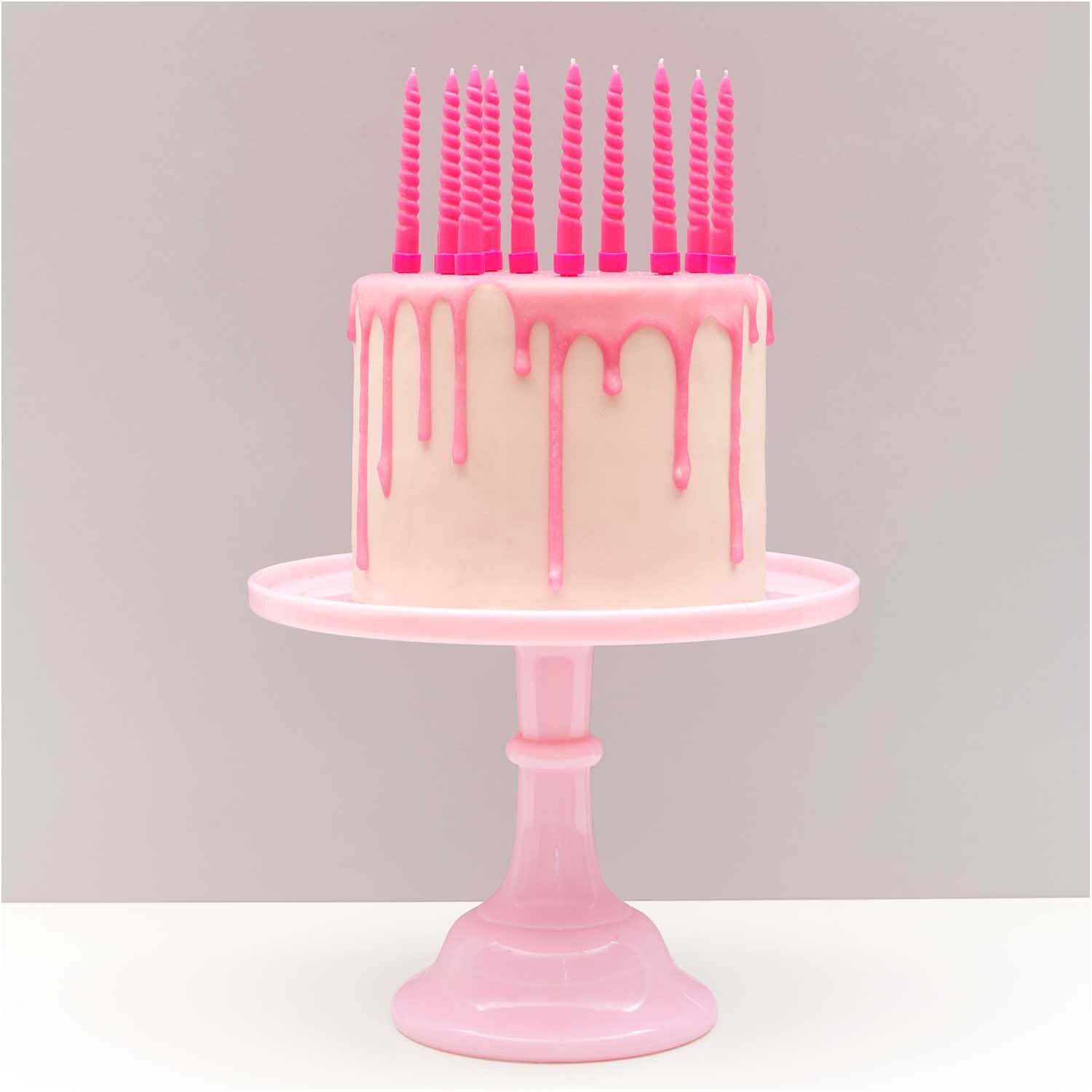 Spiralkerzen 1,2x10cm 10 Stück in Neon Pink auf einer Torte mit rosa Glasur auf rosa Tortenständer.