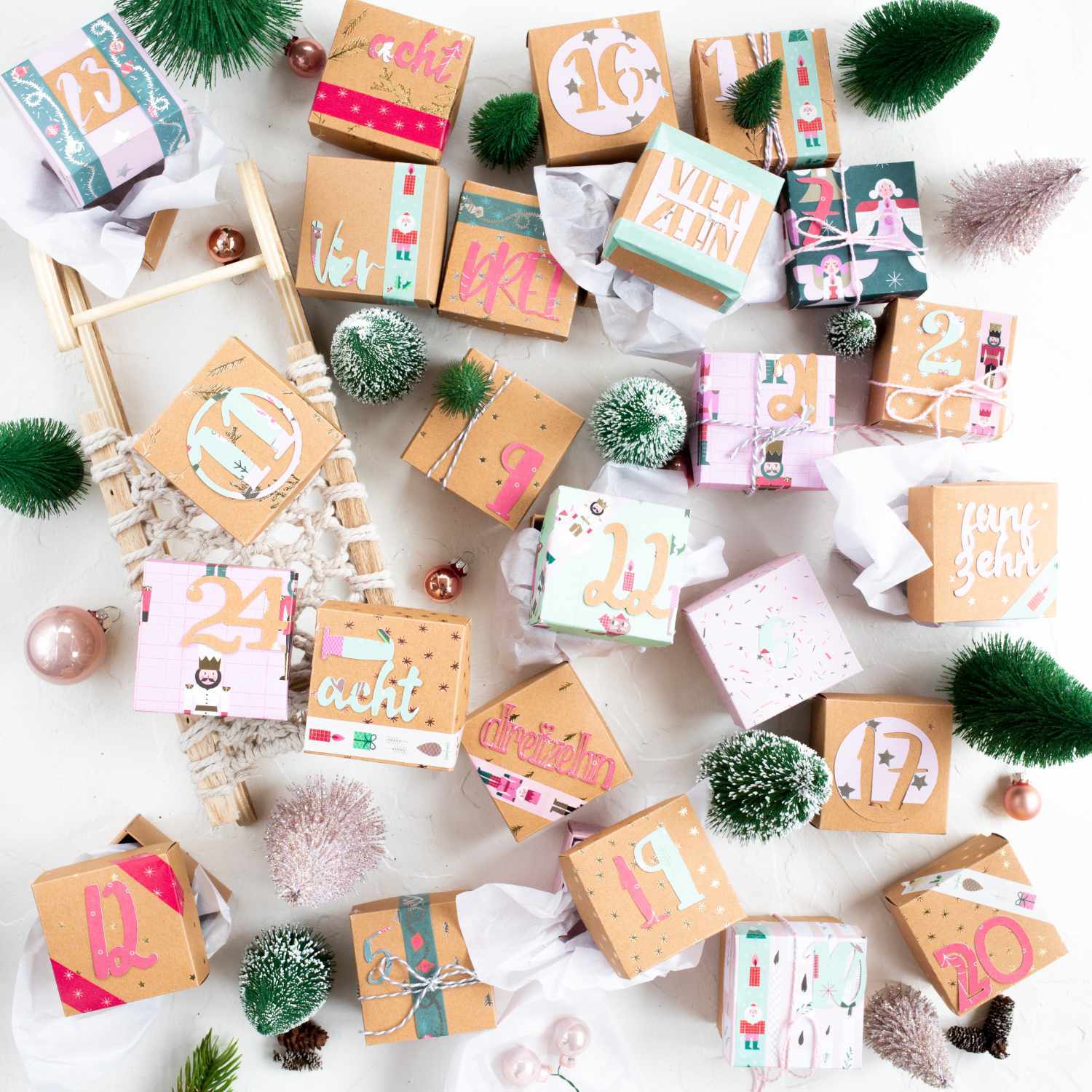 Bastelanleitung Adventskalender: Kreativ gestaltete Boxen mit Zahlen und festlichen Motiven, umgeben von Tannenzweigen und Dekoration.