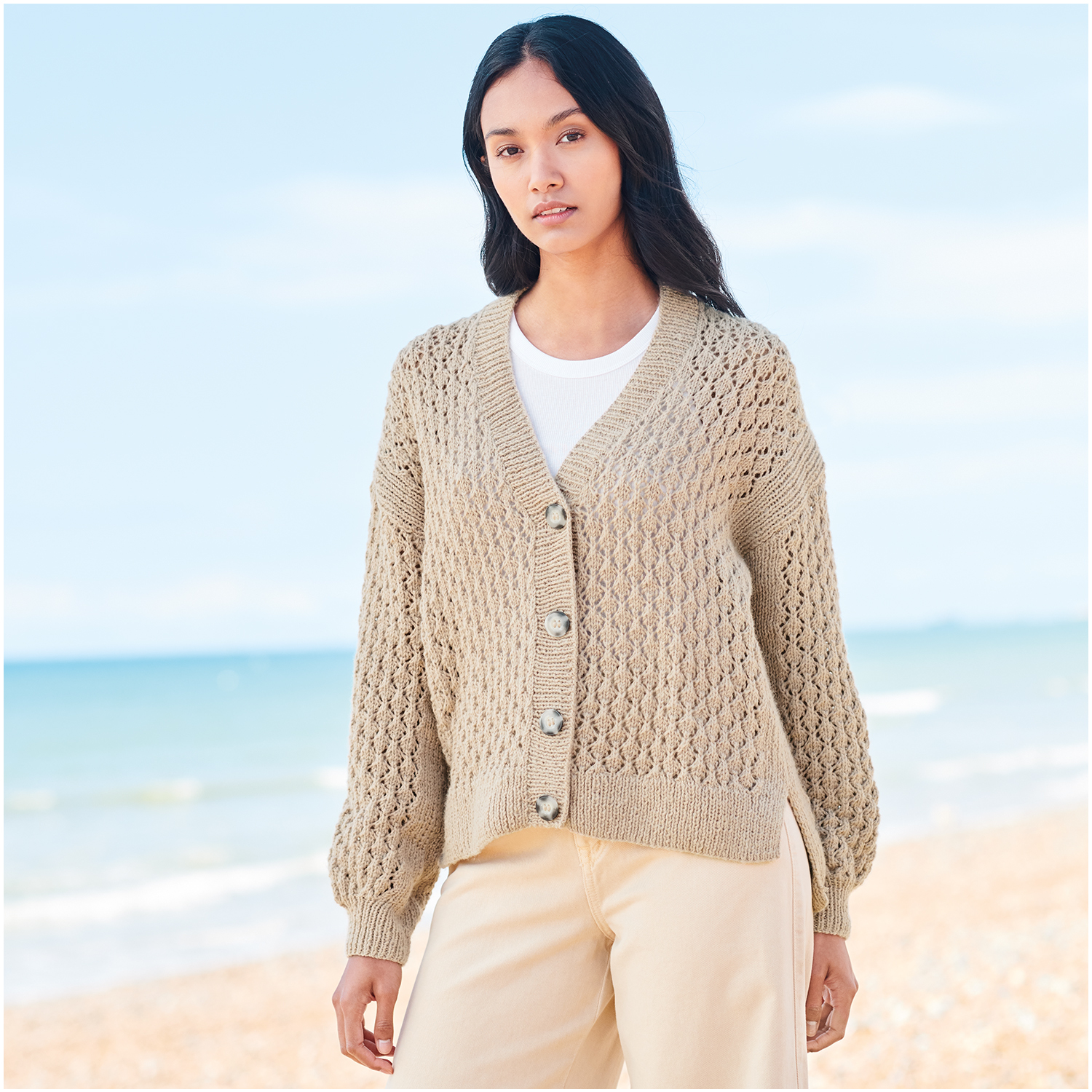 Strickset Jacke Modell 21 aus Lovewool Nr. 18: Beige Strickjacke am Strand getragen, ideal für kühle Tage.