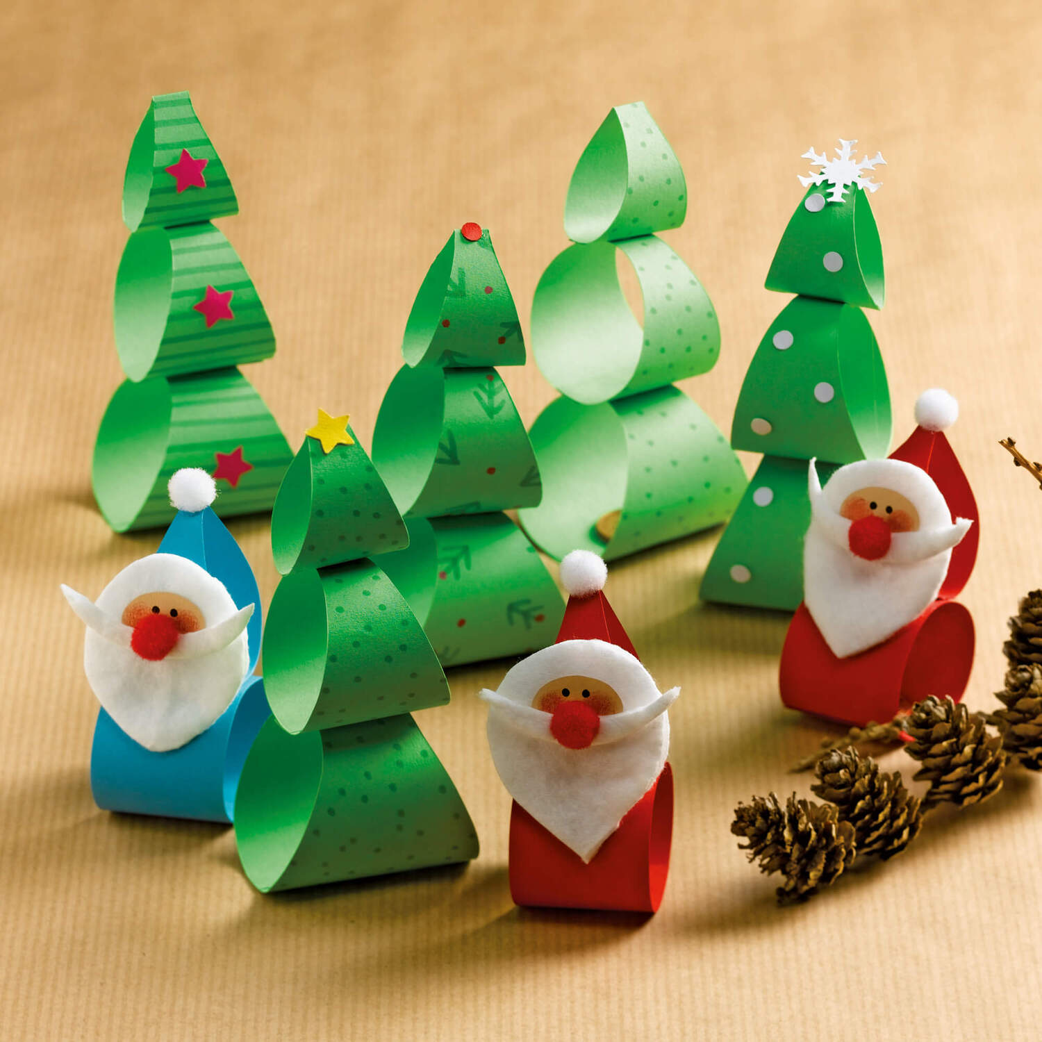 Bastelanleitung Xmas-Wackelfiguren: Bunte Weihnachtsbäume und Wichtel aus Papier auf braunem Hintergrund.