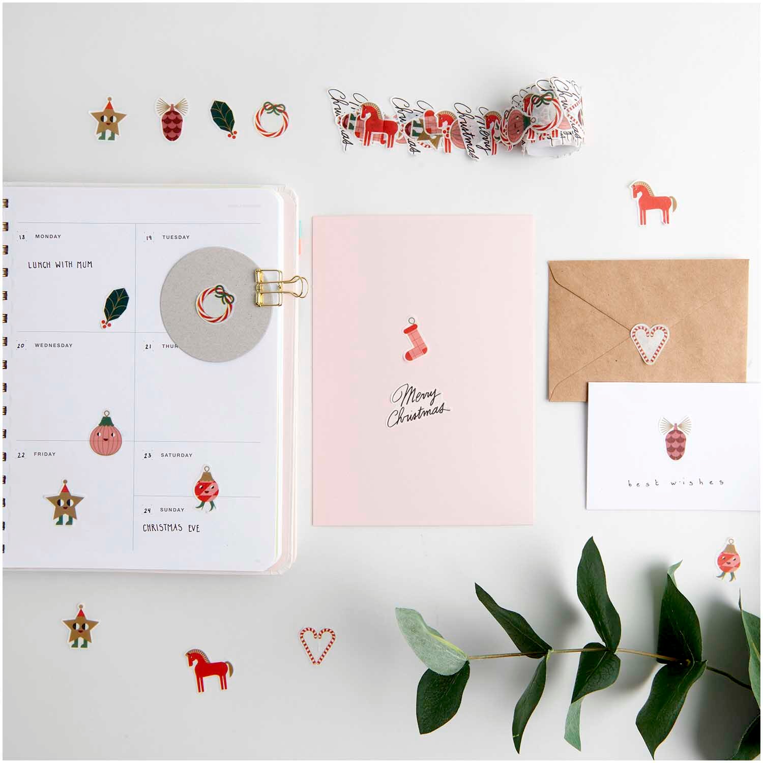 Paper Poetry Washi Sticker Figuren Christmas Rocks! 200 Stück, dekoriert auf einem Tisch mit Notizbuch, Karten und Pflanzen, von Rico Design.