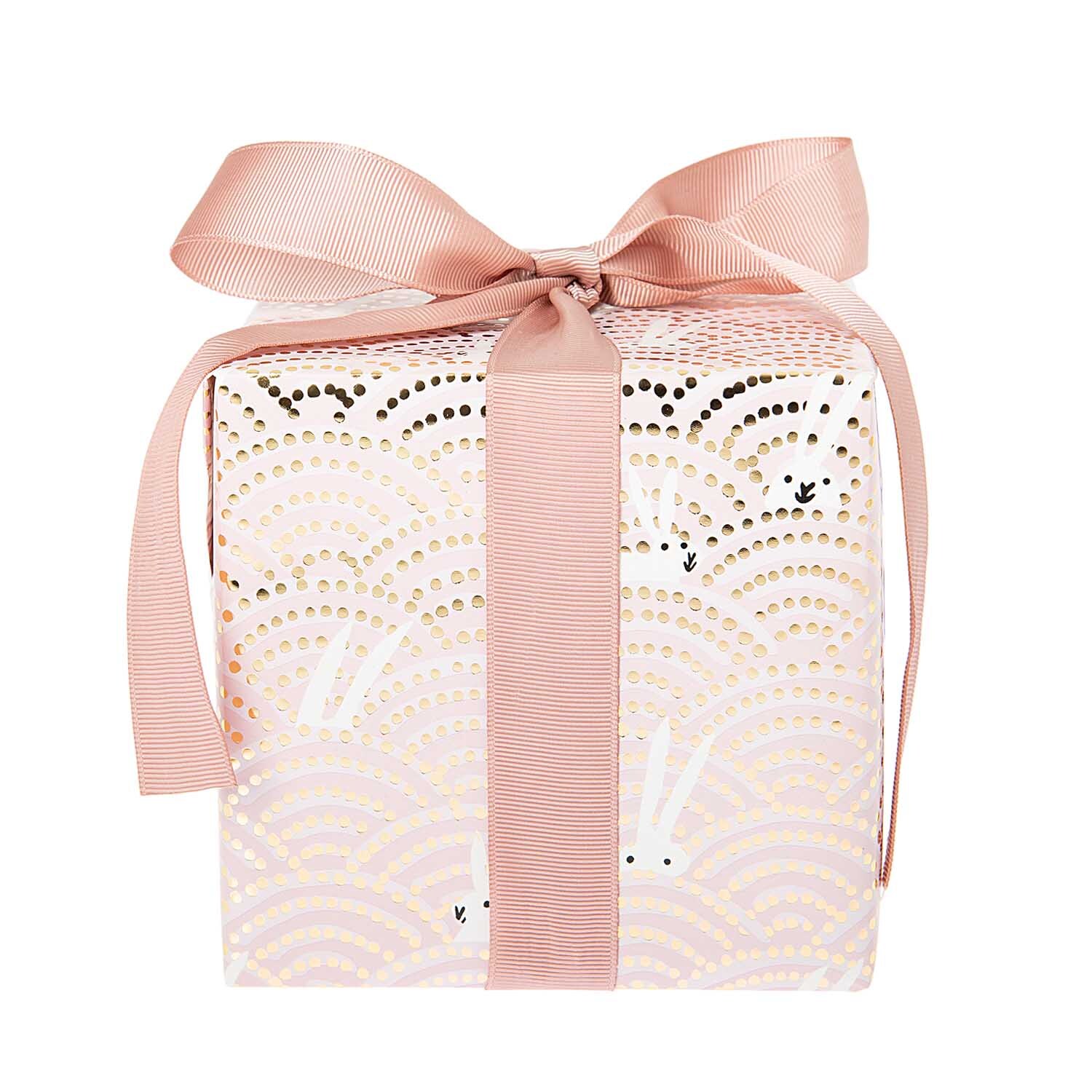 Paper Poetry Geschenkpapier zeigt Hasen im Feld mit rosa Schleife, ideal für stilvolle Geschenke.