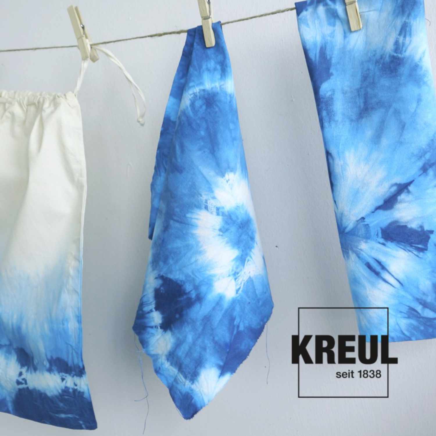Javana Batik-Textilfarbe: Blau gefärbte Stoffe an Wäscheleine, KREUL-Logo sichtbar.