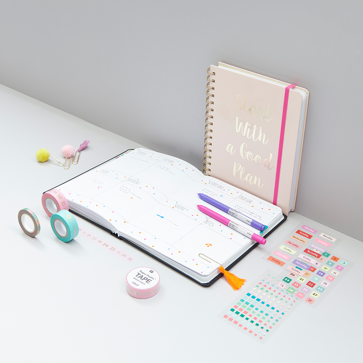 Offenes Bullet Diary mit zwei Stiften, Sticker und Tapes. Fotosetting graue Ecke.