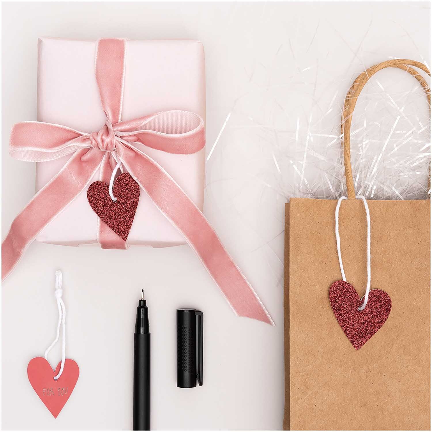 Paper Poetry Papieranhänger Herzen Glitter rot, dekoriert auf Geschenk und Tüte, mit Stift.