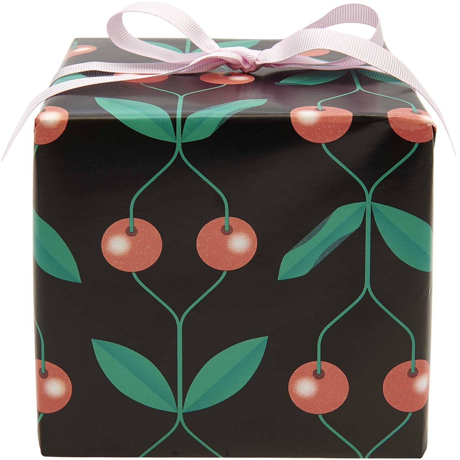Paper Poetry Geschenkpapier mit Kirschmuster auf schwarzem Hintergrund, dekoriert mit rosa Schleife. Ideal für stilvolle Geschenke.