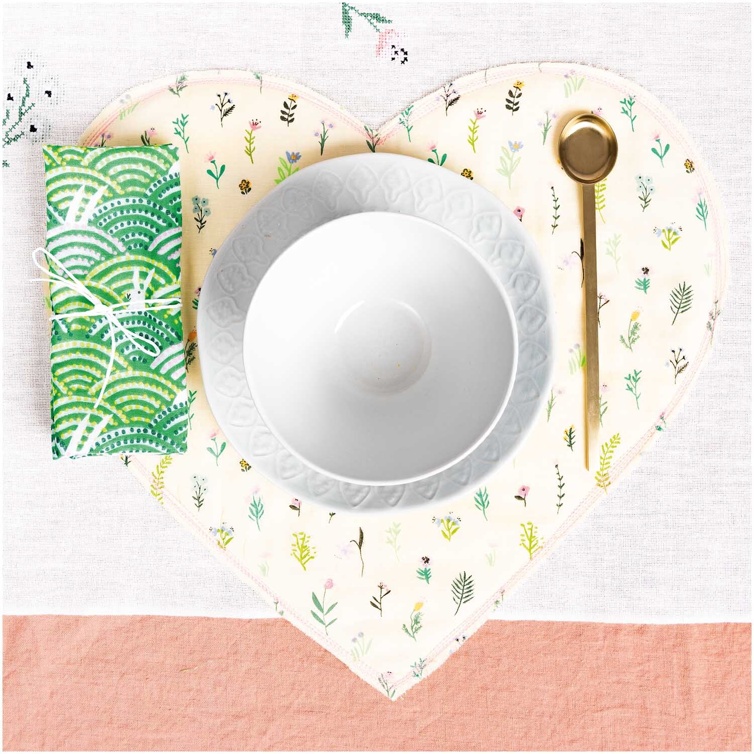 Musselin-Druckstoff Bunny Hop Streublumen in Herzform mit Geschirr und Besteck auf Tisch.