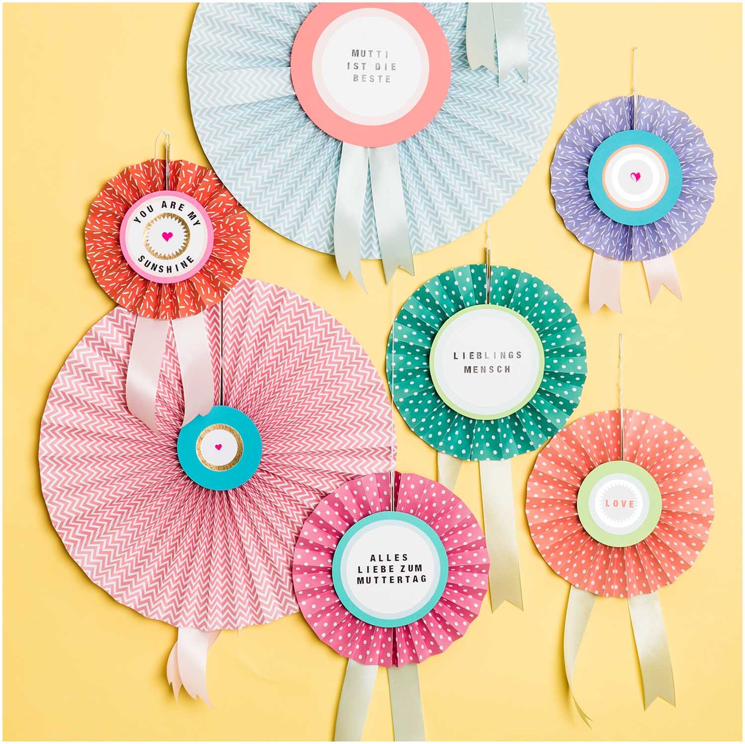Paper Poetry Bastelkartonblock zeigt bunte, dekorative Rosetten mit Botschaften auf gelbem Hintergrund.