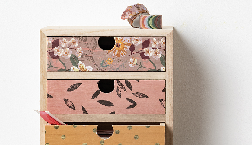 Bastelanleitung Schreibtischutensilien individualisieren: Holzschubladen mit floralen und geometrischen Mustern, dekoriert mit Washi-Tape.