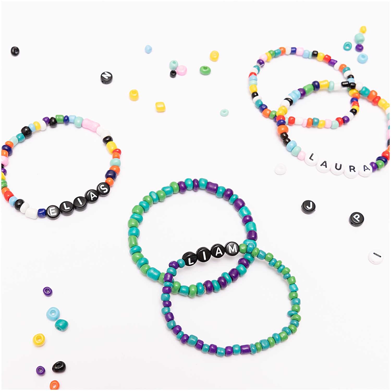 Perlen Buchstaben-Mix rund ca. 165 Stück von Rico Design. Bunte Armbänder mit Namen aus schwarzen Buchstabenperlen auf weißem Hintergrund.