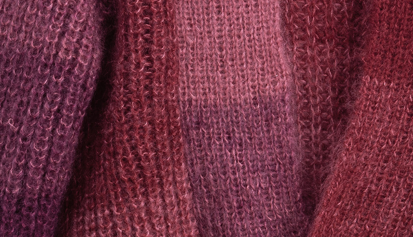 Strickanleitung Jacke aus Essentials Super Kid Mohair Loves Silk Colourlove, zeigt weiche, mehrfarbige Stricktextur in Rottönen.