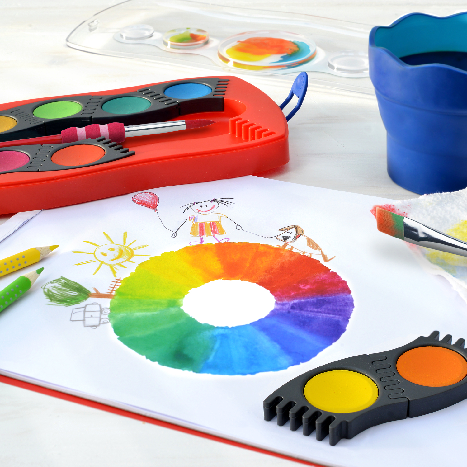 Colour Grip 2001: Kinderzeichnung mit buntem Farbkreis, Wasserfarben und Pinseln auf einem Tisch.