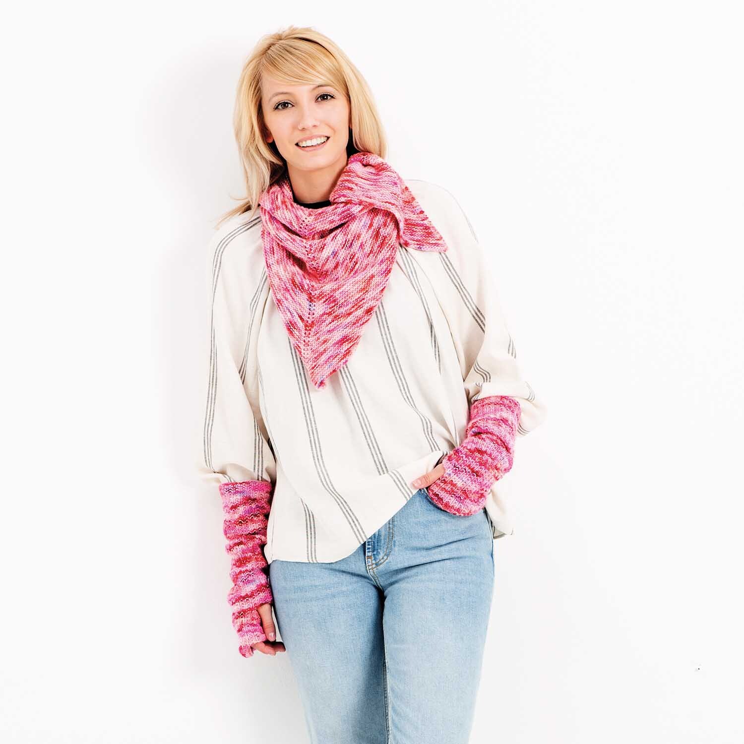 Luxury Hand-Dyed Happiness dk: Frau trägt gestrickten Schal und Armstulpen in Rosa von Rico Design, kombiniert mit lässiger Kleidung.