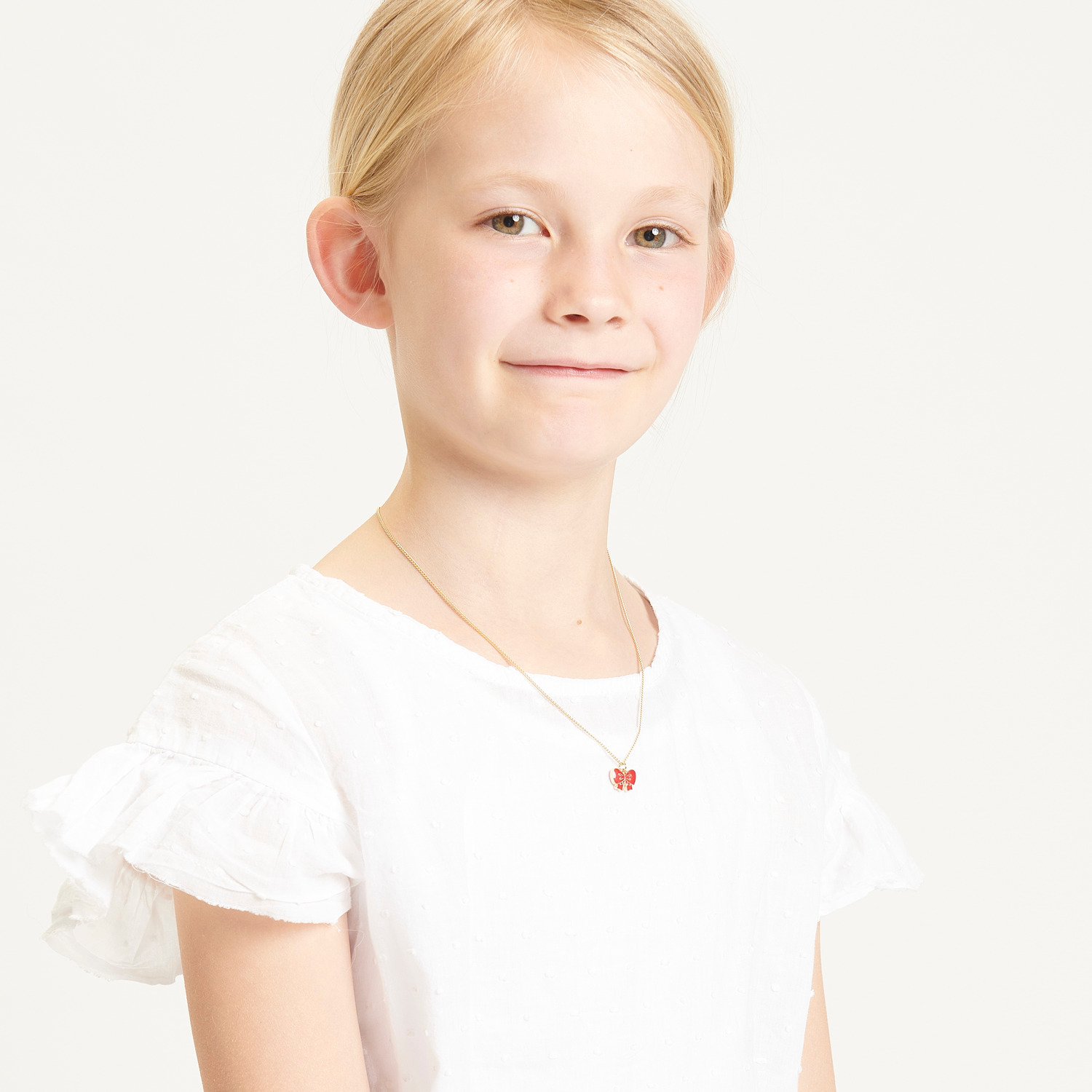 Kette mit Anhänger Schleife, 40cm, in elegantem Rot, getragen von einem Kind in weißem Kleid.