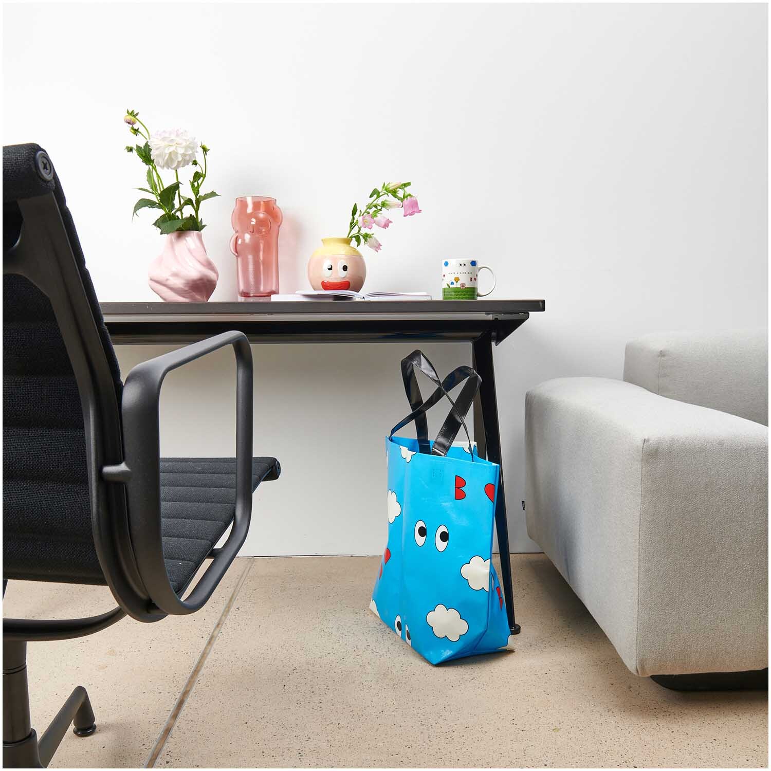Rico Design x Redfries Shopper Wolken blau steht neben einem modernen Schreibtisch mit Blumen.