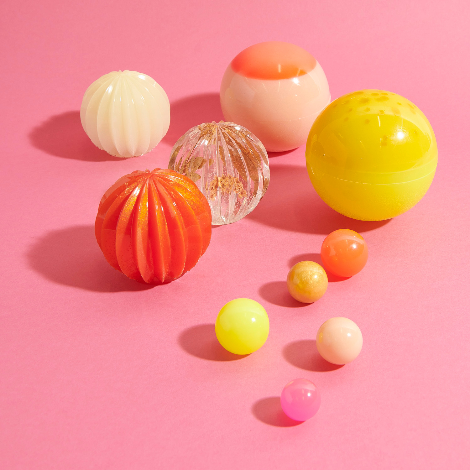 Silikon Gießform Kugel mit Streifen: Verschiedene bunte Kugeln auf rosa Hintergrund, ideal für kreative Resin-Projekte.