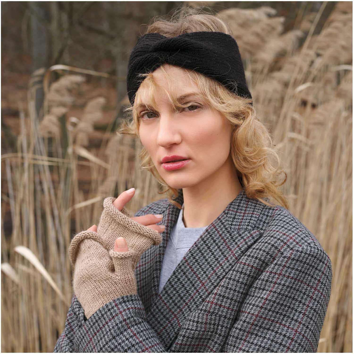 Strickset Stulpen Modell 24: Frau mit beigen Stulpen und schwarzem Stirnband vor Schilfgras.