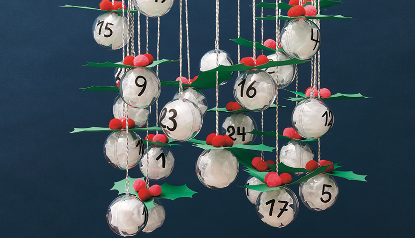 Bastelanleitung Adventskalender aus Acrylkugeln: Hängende Kugeln mit Zahlen, dekoriert mit grünen Blättern und roten Beeren.