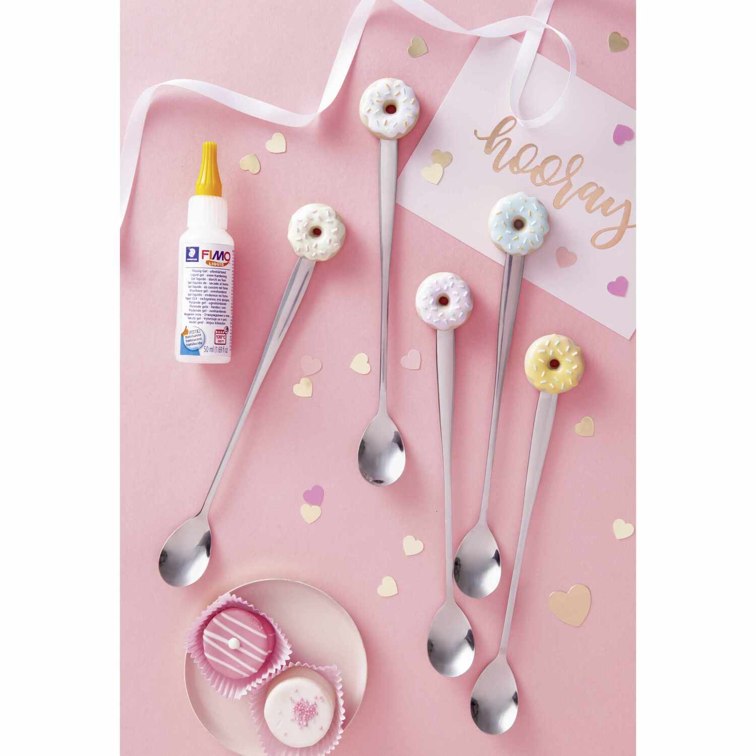 FIMO Liquid ofenhärtendes Modelliergel transparent neben dekorativen Löffeln mit Donut-Motiven auf rosa Hintergrund.