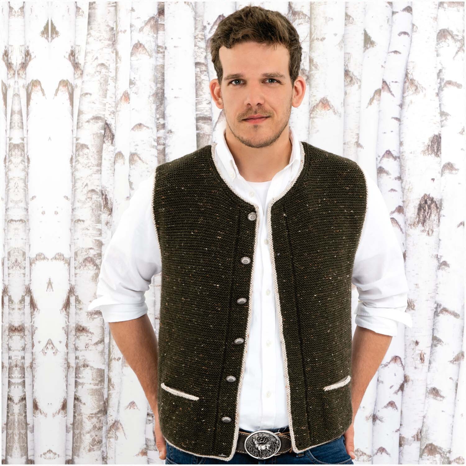 Essentials Merino Plus Tweed dk: Mann trägt eine dunkle Strickweste vor Birkenwald-Hintergrund.