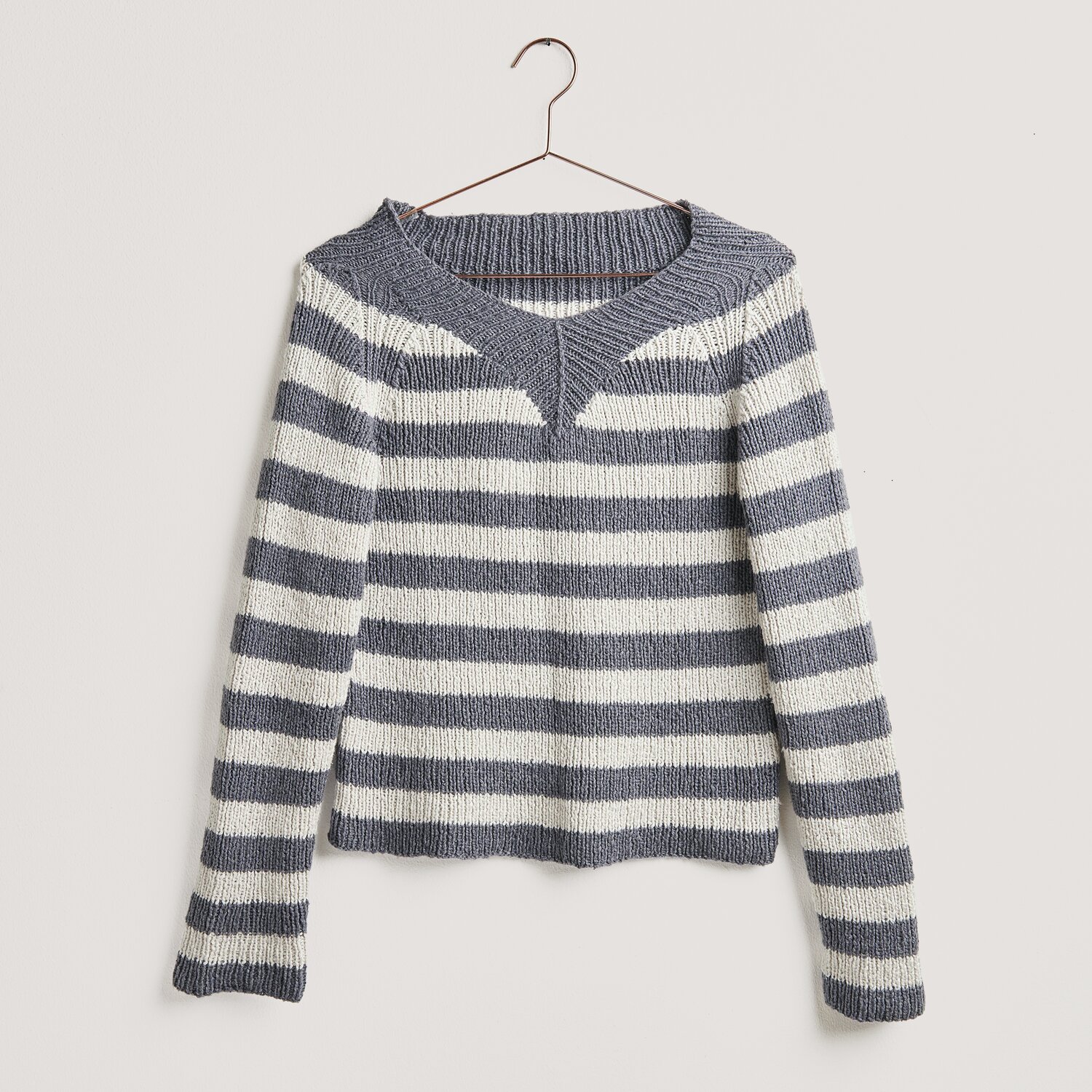 Strickset Pullover Modell 01b aus Lovewool No. 20, gestreift in Grau und Weiß, hängt an einem Kleiderbügel. Ideal für Frühjahr-Sommer.