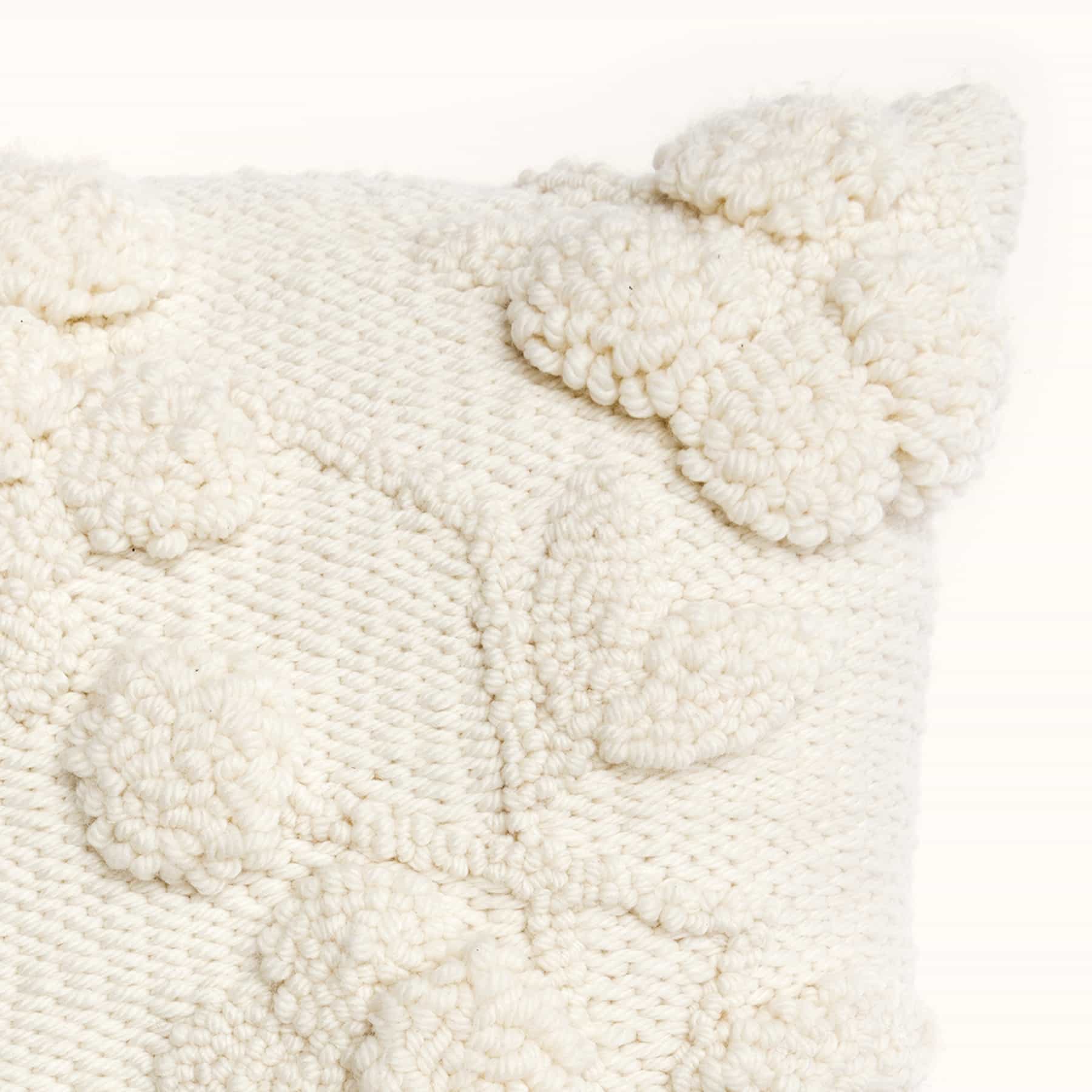 Ecke eines cremefarbigen Kissens mit Punch Needle Stickereien