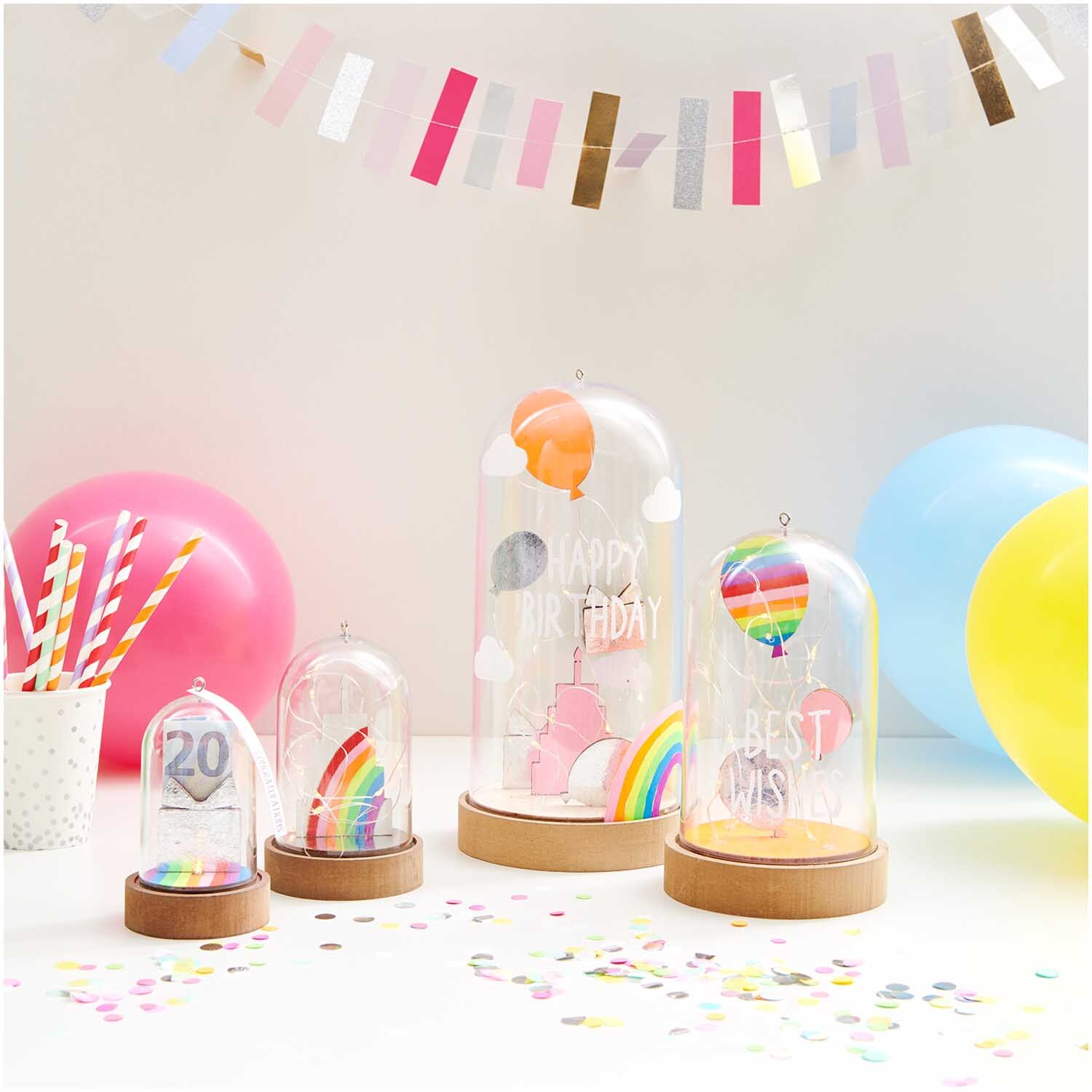 Dekohaube mit Sockel 5,5x11cm Gr. S von Rico Design zeigt bunte Ballons und Regenbogen auf einem Tisch mit Konfetti und Luftballons.