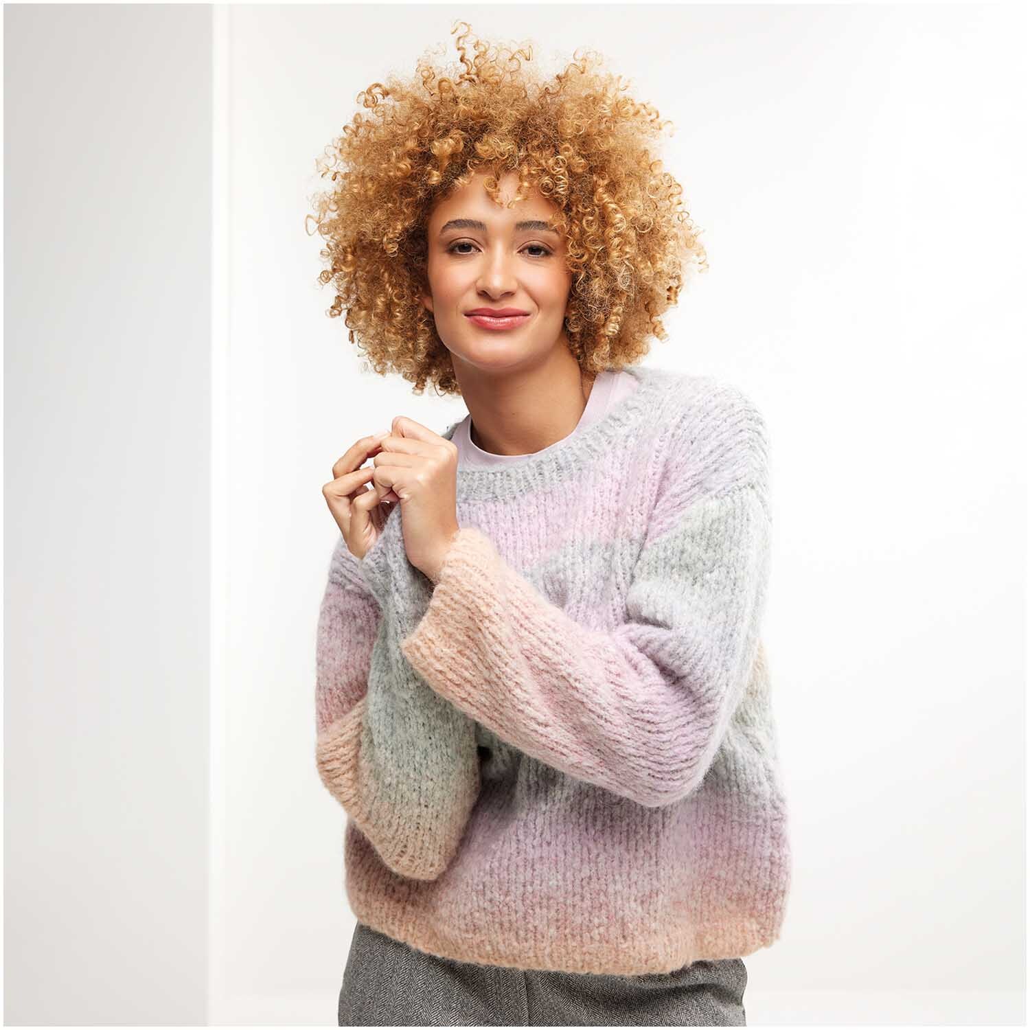 Strickset Pullover Modell 12: Frau trägt pastellfarbenen Pullover, gestrickt aus weicher Wolle.