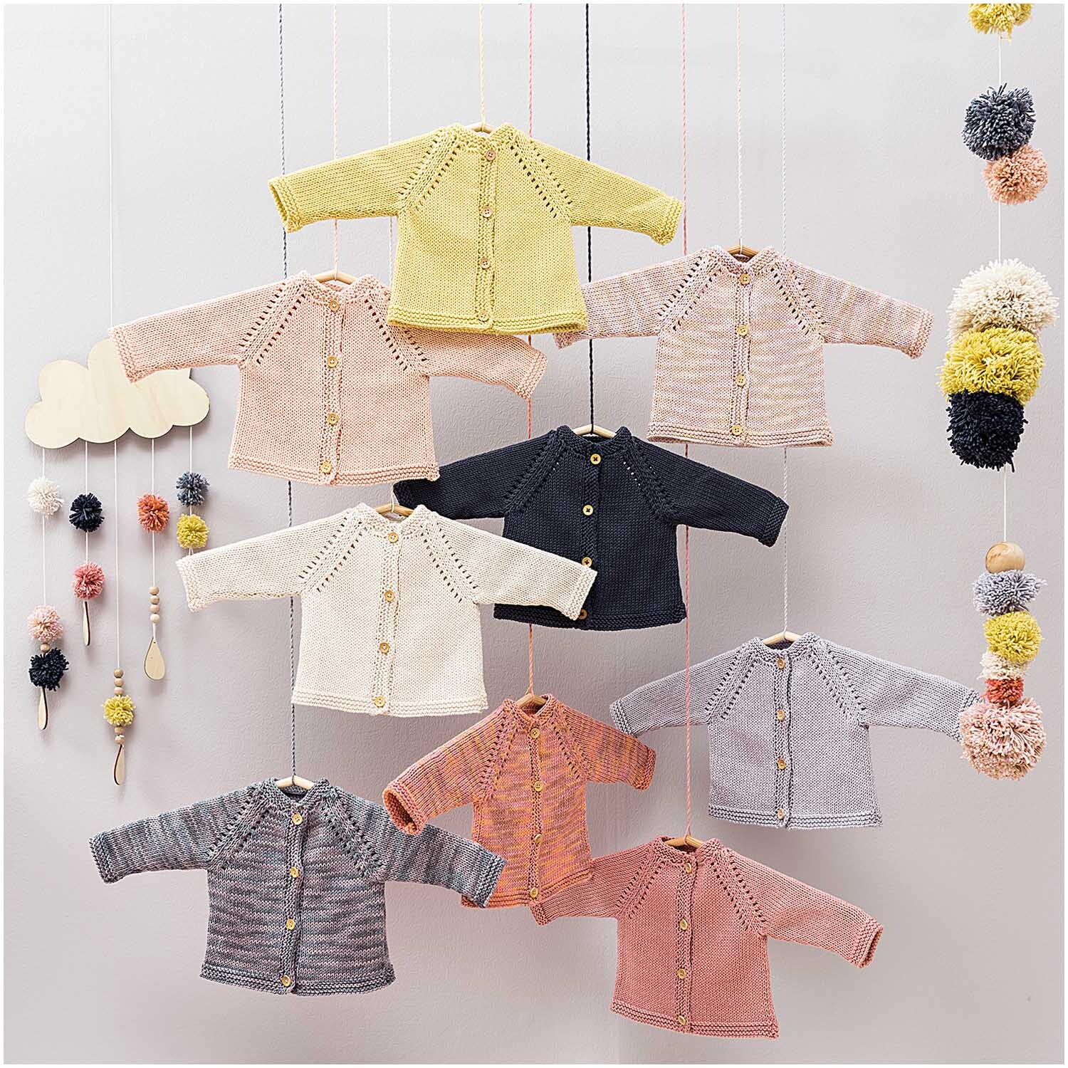 Rico Baby Cotton Soft dk: Strickjacken in Pastellfarben und Dunkelblau, dekorativ aufgehängt.