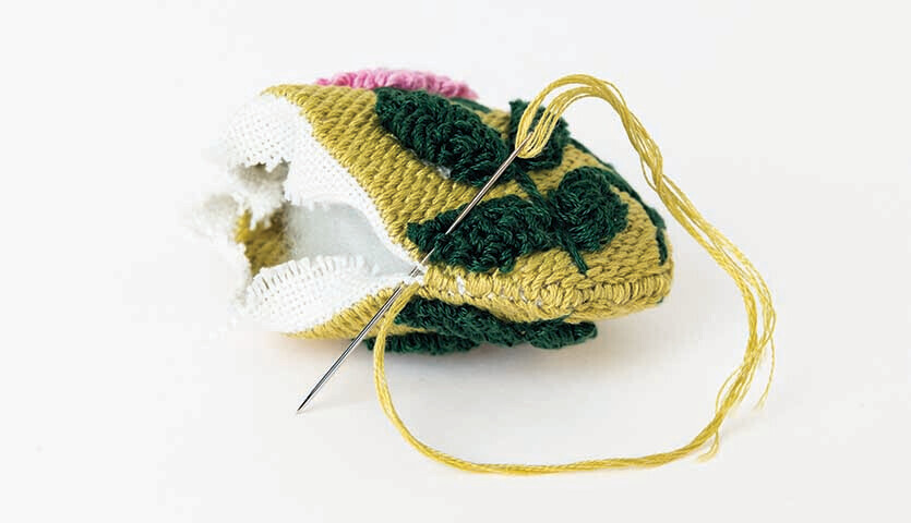 Anleitung Osteranhänger mit Punch Needle: Nahaufnahme eines bunten, gestickten Anhängers mit Nadel.