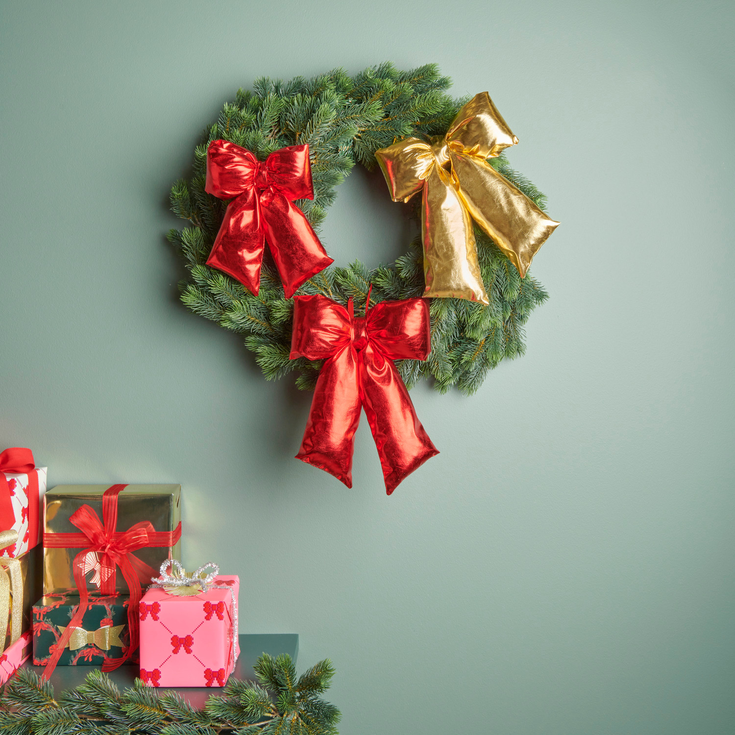 Weihnachtsschleife Rot: Festlicher Kranz mit roten und goldenen Schleifen, dekoriert auf grünem Hintergrund.