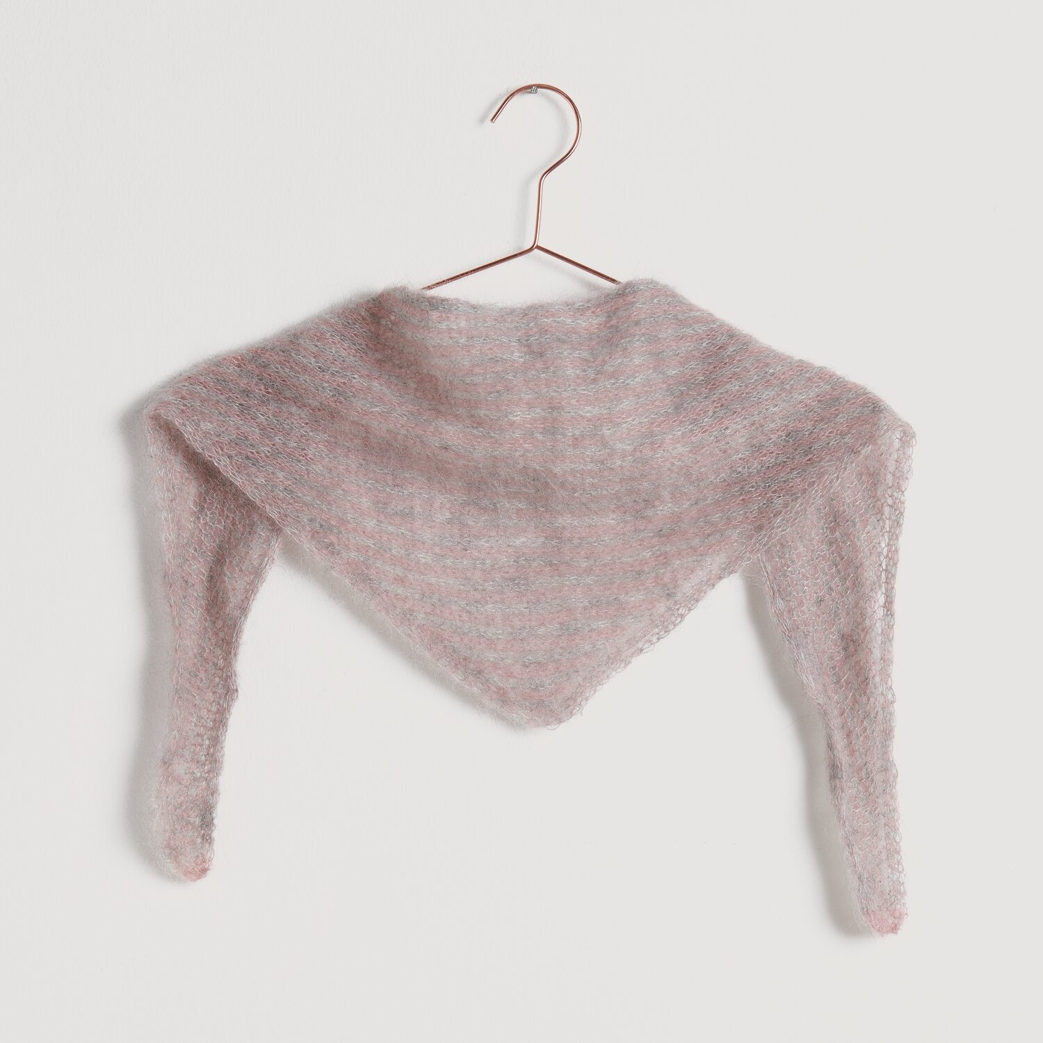 Strickset Mini-Tuch Modell 06: Weiches, dreieckiges Tuch in zartem Rosa, aufgehängt an einem Kleiderbügel.