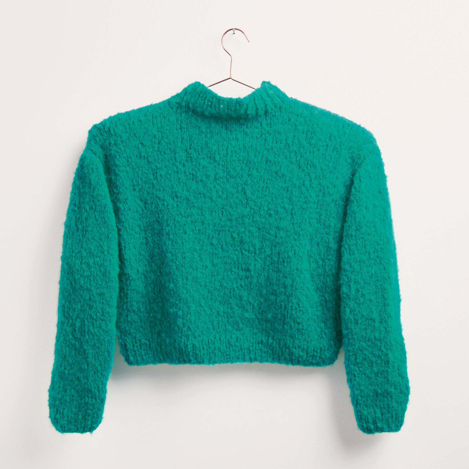 Made by Me Handknitting No. 19 Pullover in leuchtendem Türkis, präsentiert auf einem Kleiderbügel. Ideal für Herbst-Wintermode.