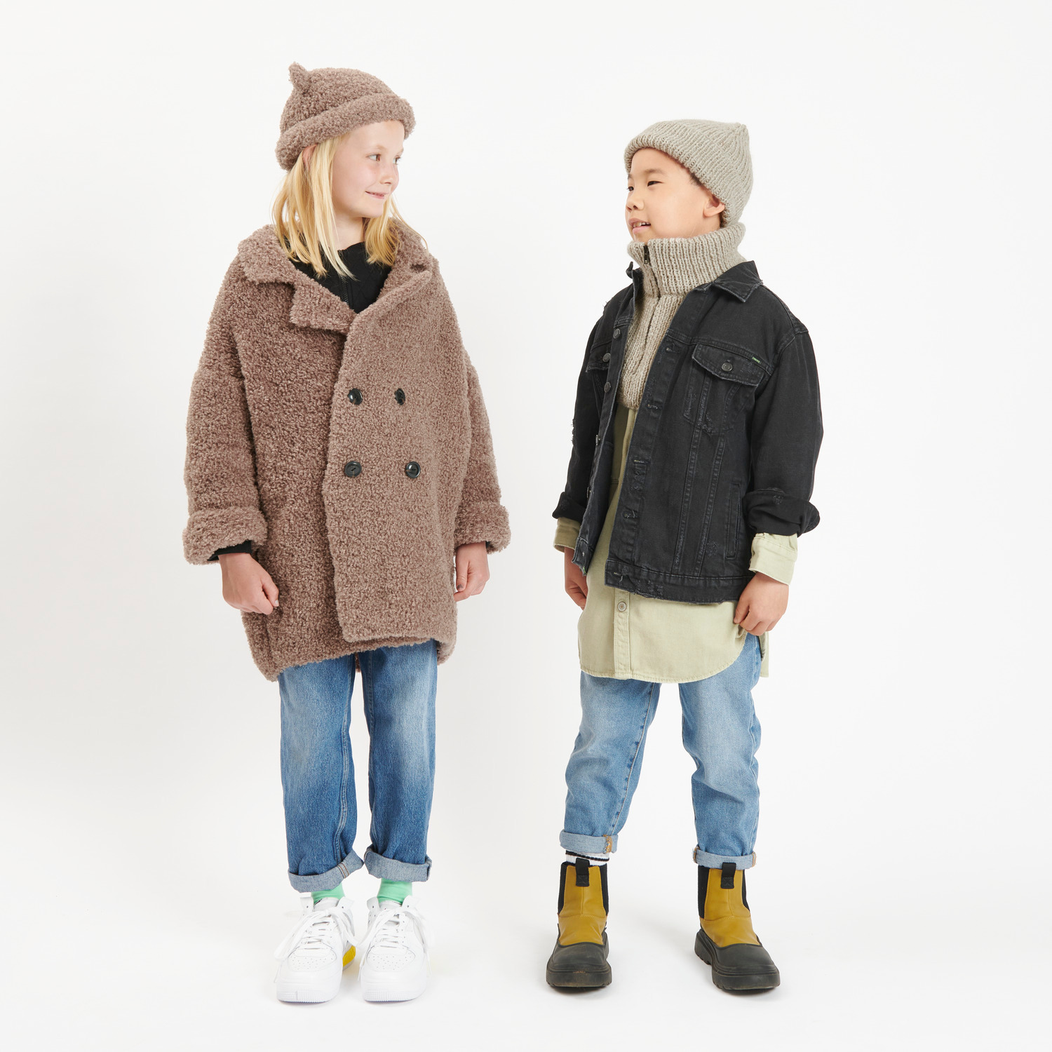 Rico Kids 13: Zwei Kinder in modischer Winterkleidung, brauner Mantel, schwarze Jacke, beige Mützen.
