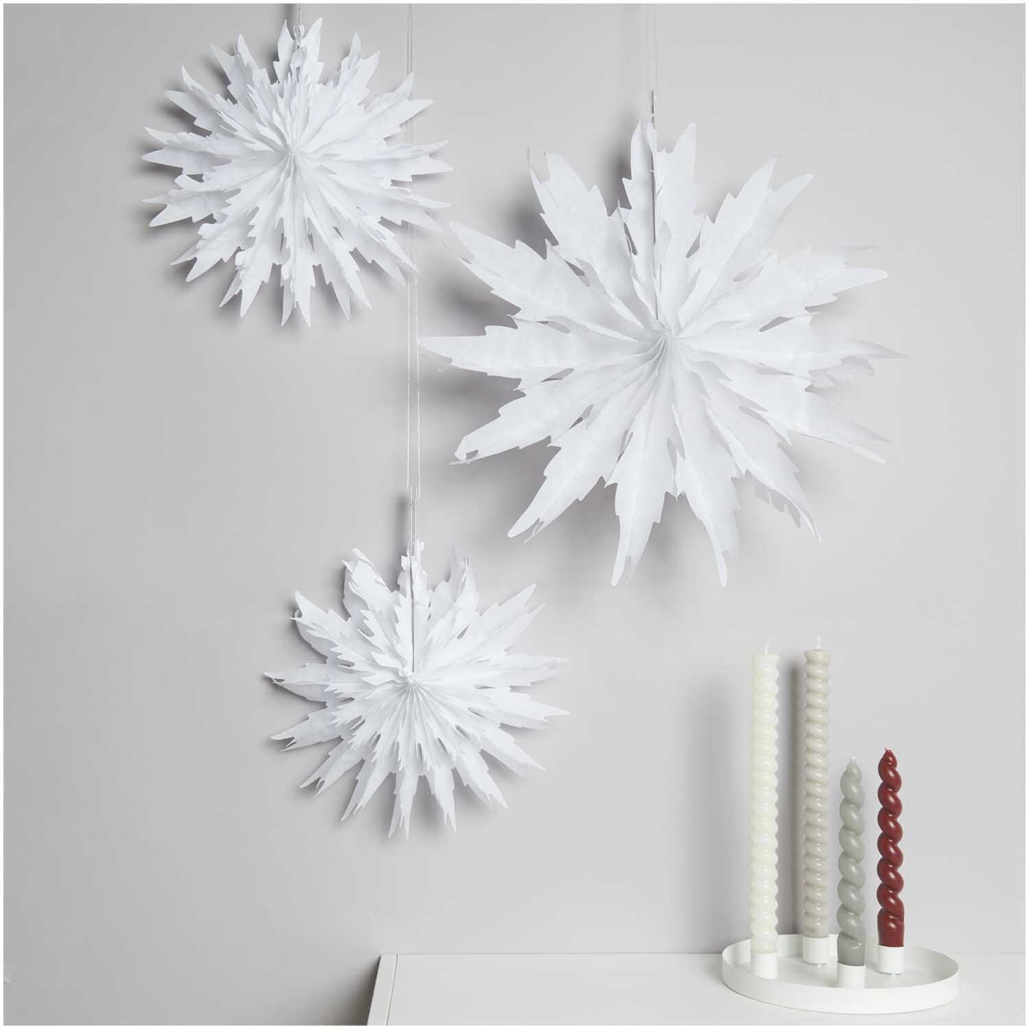 Wabenpapiersterne Eiskristall weiß 3 Stück von Rico Design hängen dekorativ an der Wand.