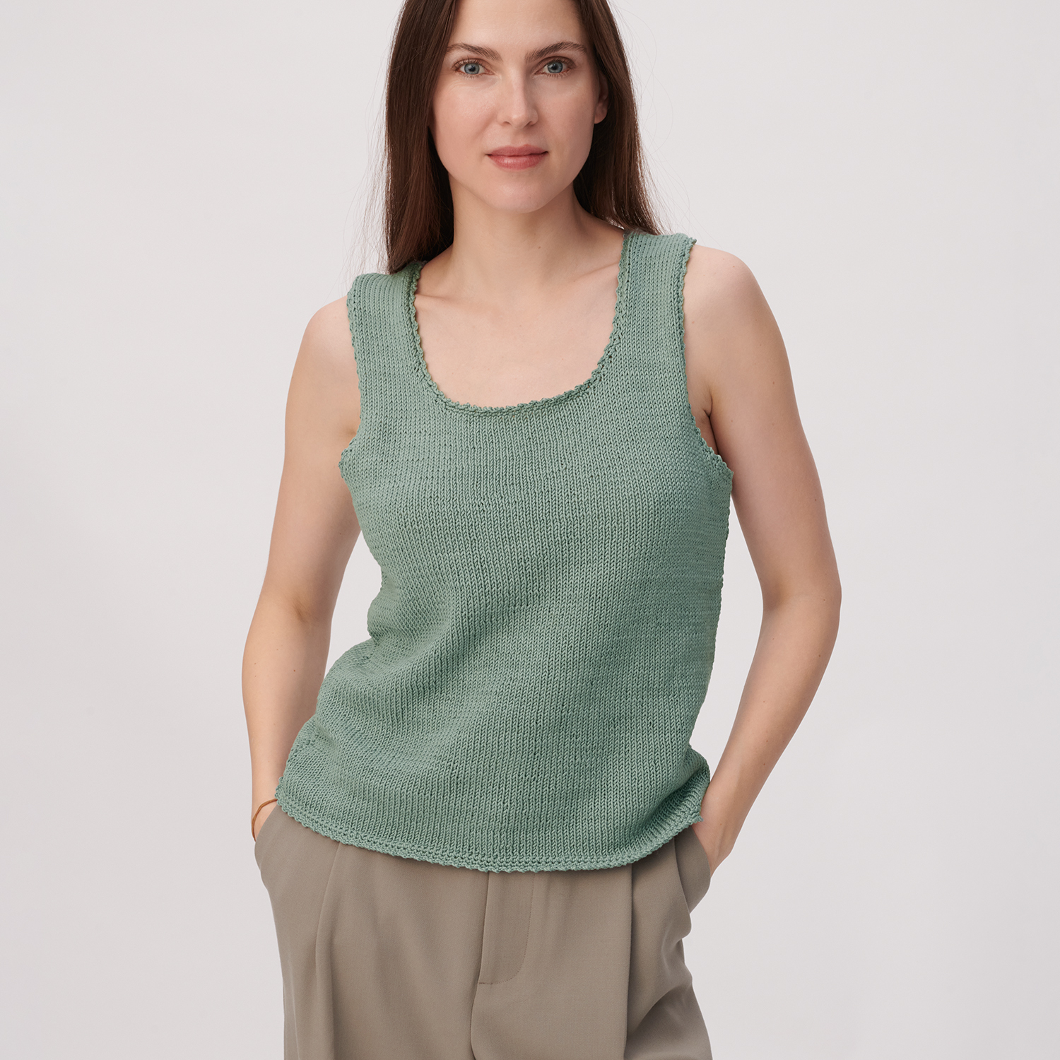 Strickanleitung Top mit Racerback aus Mille Fili: Frau trägt grünes Stricktop, kombiniert mit beigen Hosen.