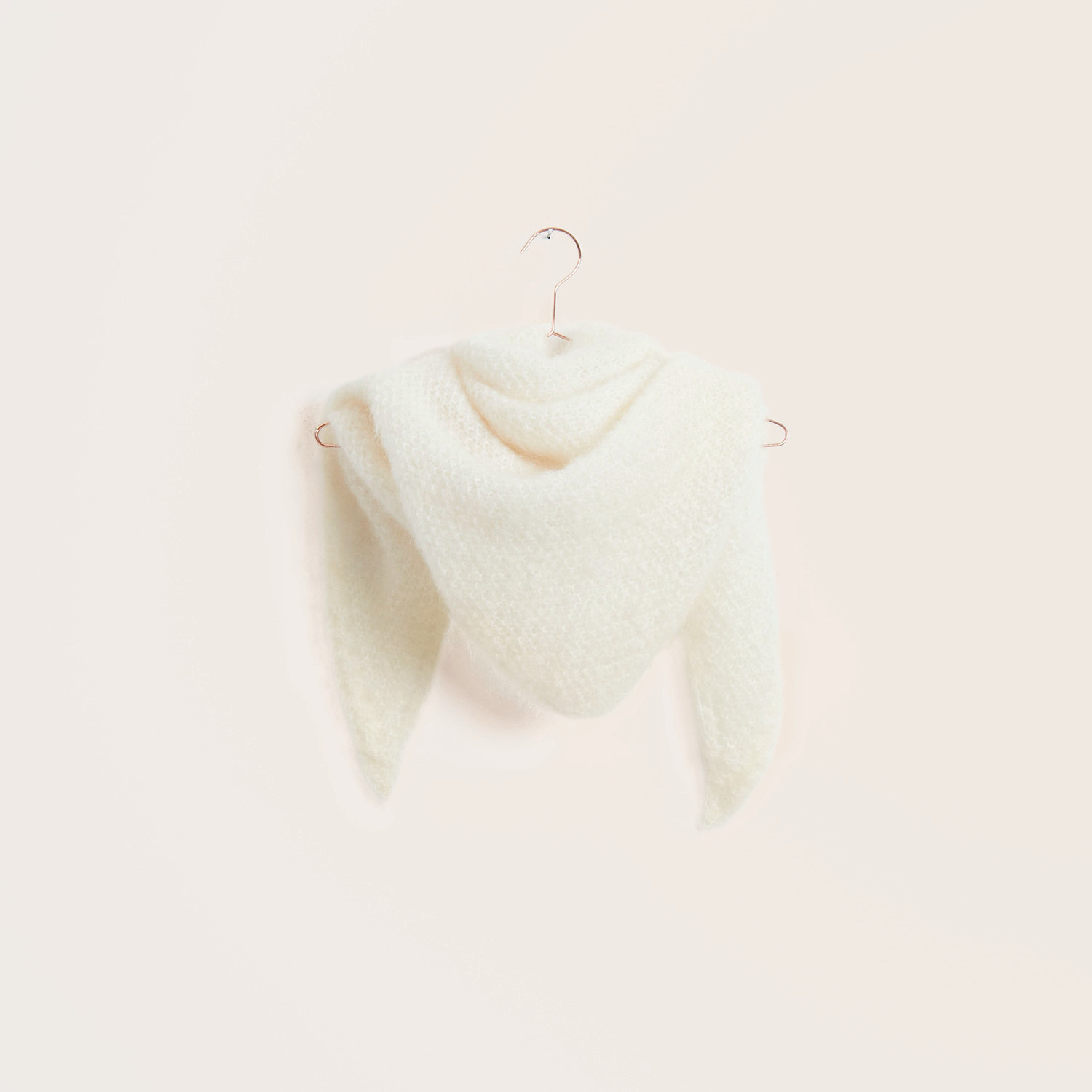 Strickset Dreieckstuch Modell 13a aus Trachtenbuch I mog di in Creme, aus Mohair Merino Chunky, präsentiert auf einem Kleiderbügel.