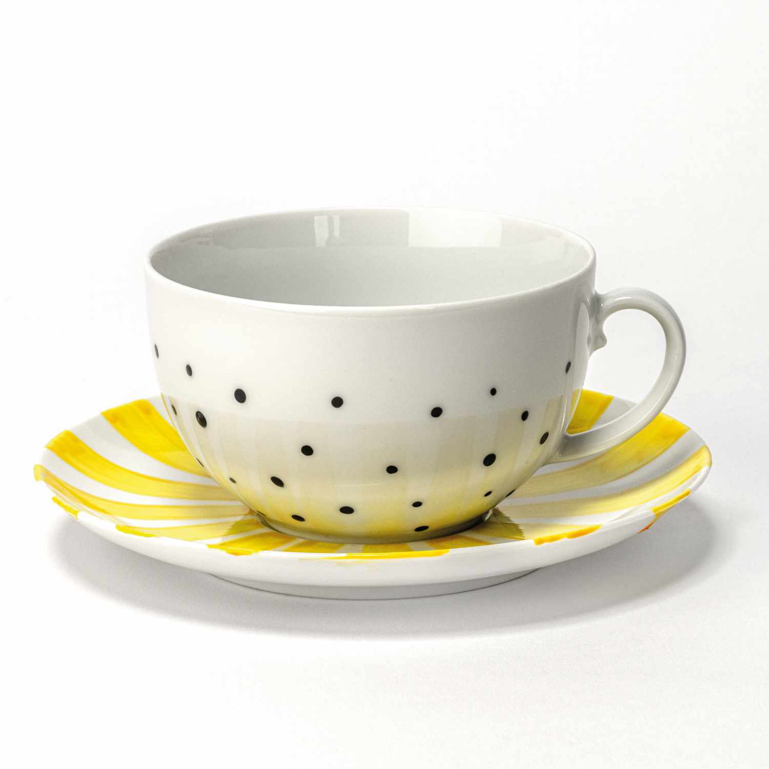 Porcelain & Glass Starterset glossy: Weiße Tasse mit schwarzen Punkten auf gelbem, gestreiftem Unterteller. Marke: Marabu.