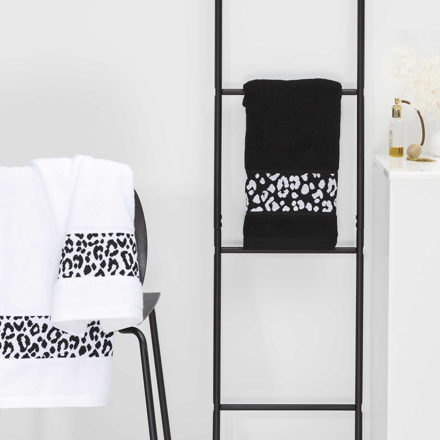 Handtuch 50x100cm von Rico Design in Schwarz mit Leopardenmuster, dekorativ auf Leiter drapiert.