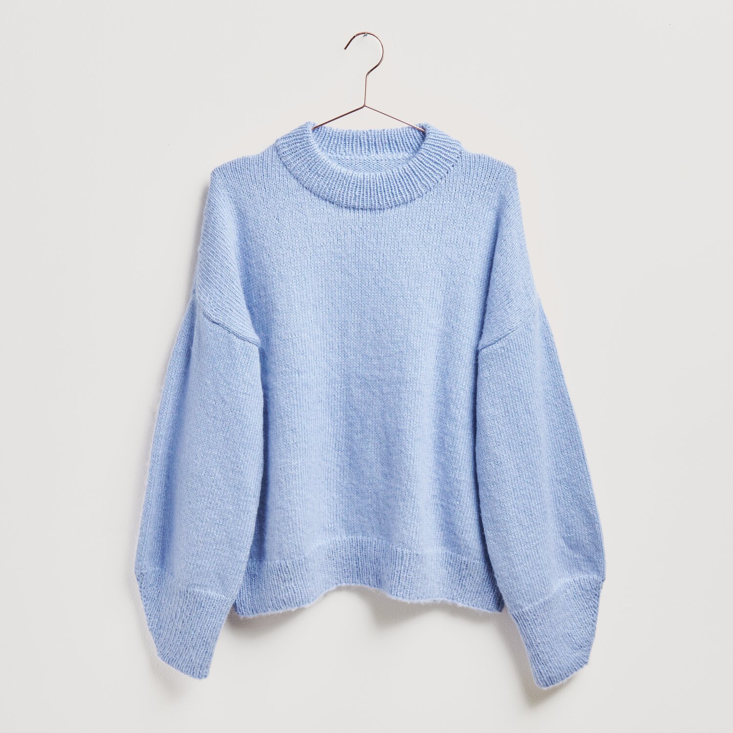 Strickset Pullover Modell 06 in Lavendel von Rico Design, präsentiert auf einem Kleiderbügel.