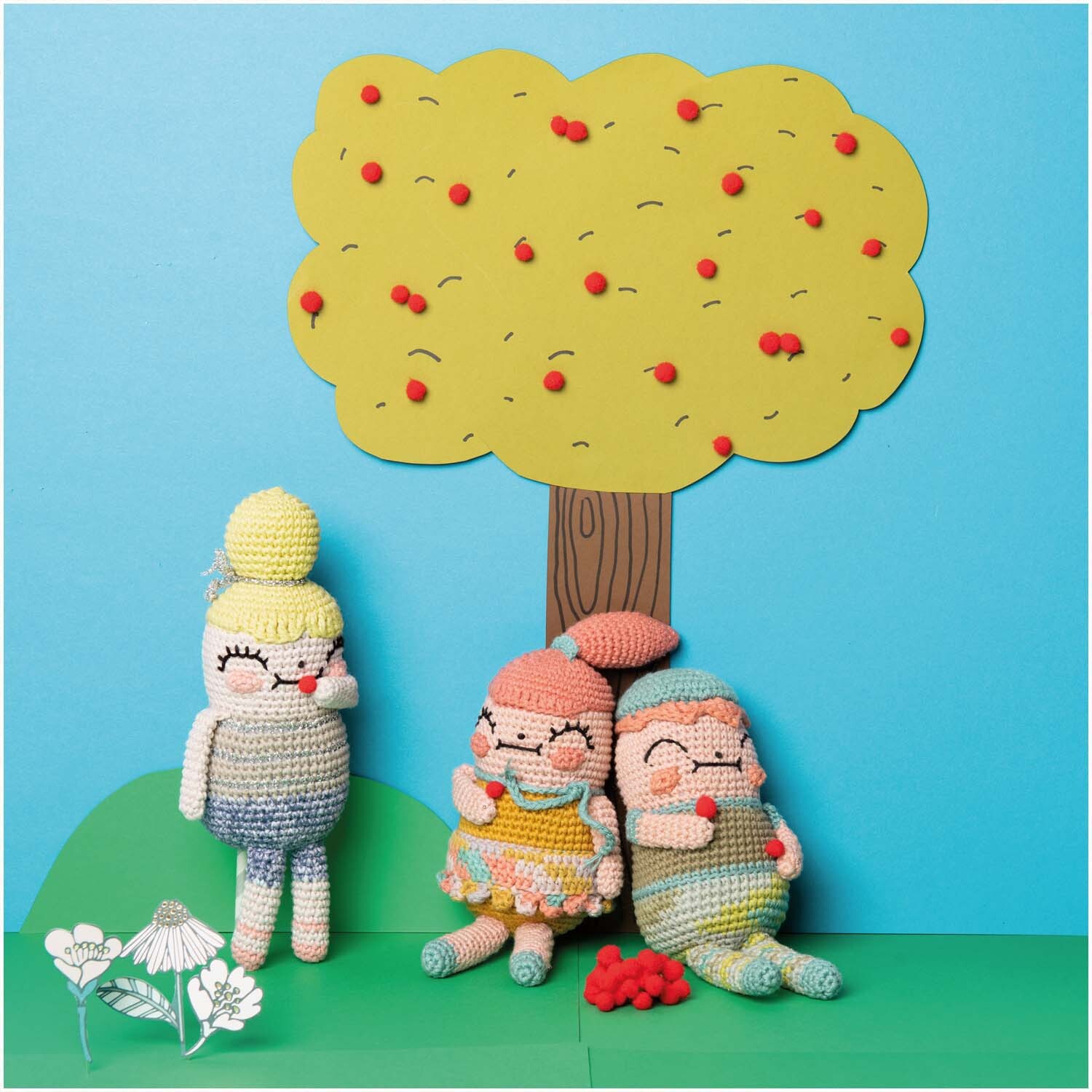 Ricorumi Crazy Cute Family: Drei gehäkelte Figuren sitzen fröhlich unter einem bunten Baum.