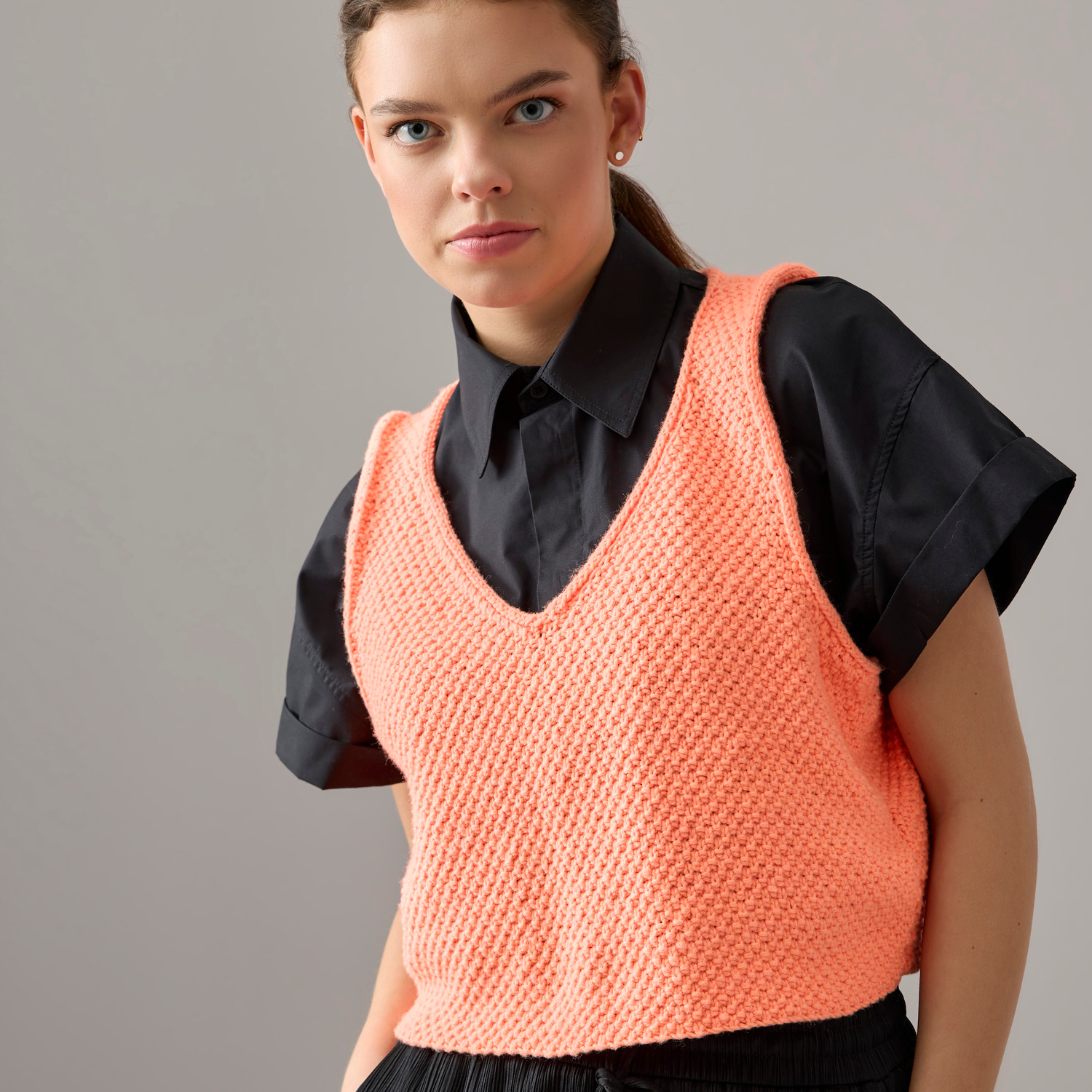 Special "Vegan Cashmere" International: Frau trägt orangefarbenes Stricktop über schwarzer Bluse.