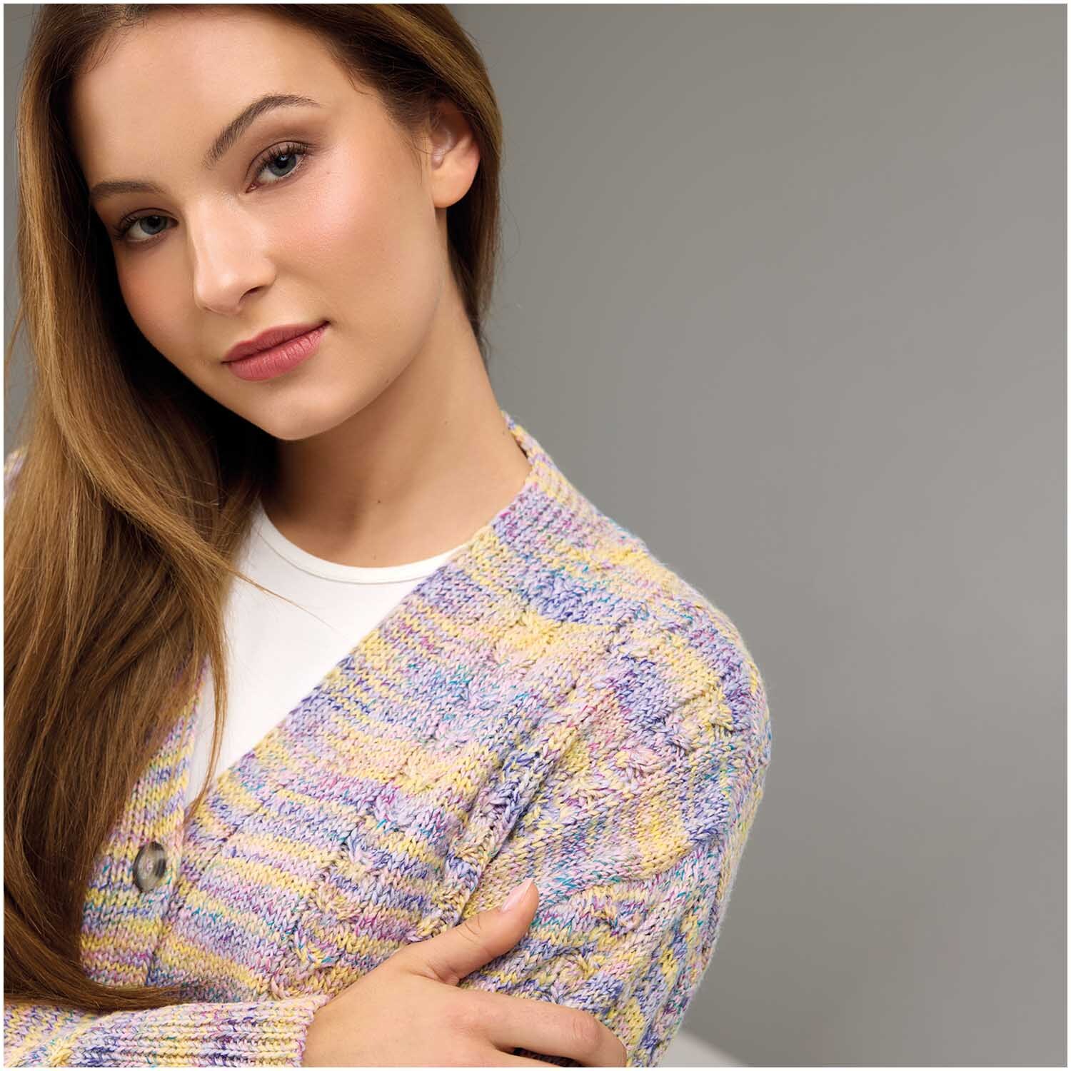 Strickset Jacke Modell 06: Frau trägt eine bunte Strickjacke in Pastelltönen, die elegant und modern wirkt.