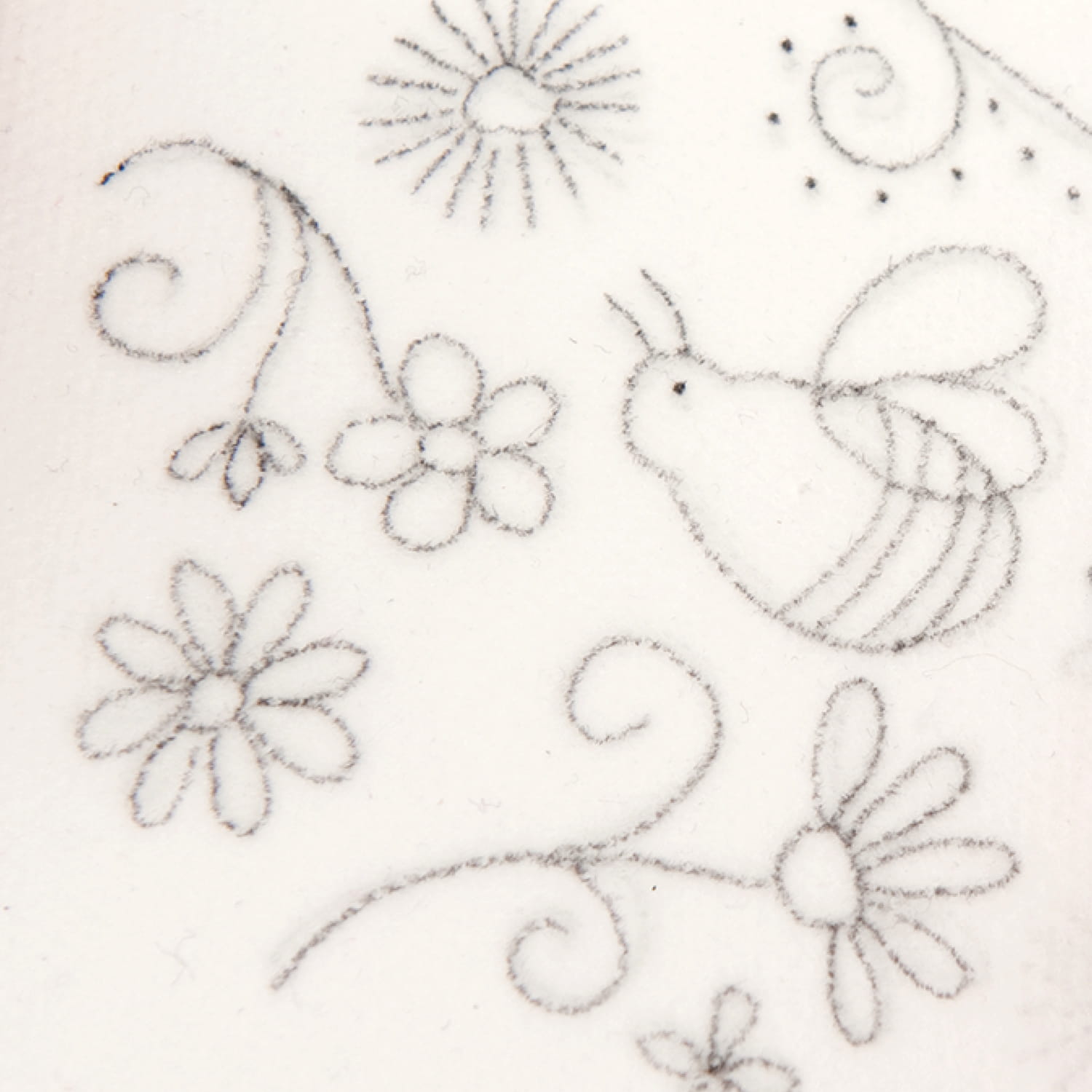 Eine Vorlage mit Bienen und Blumen-Motiv wird mit einem Bleistift auf Solufix Vlies übertragen
