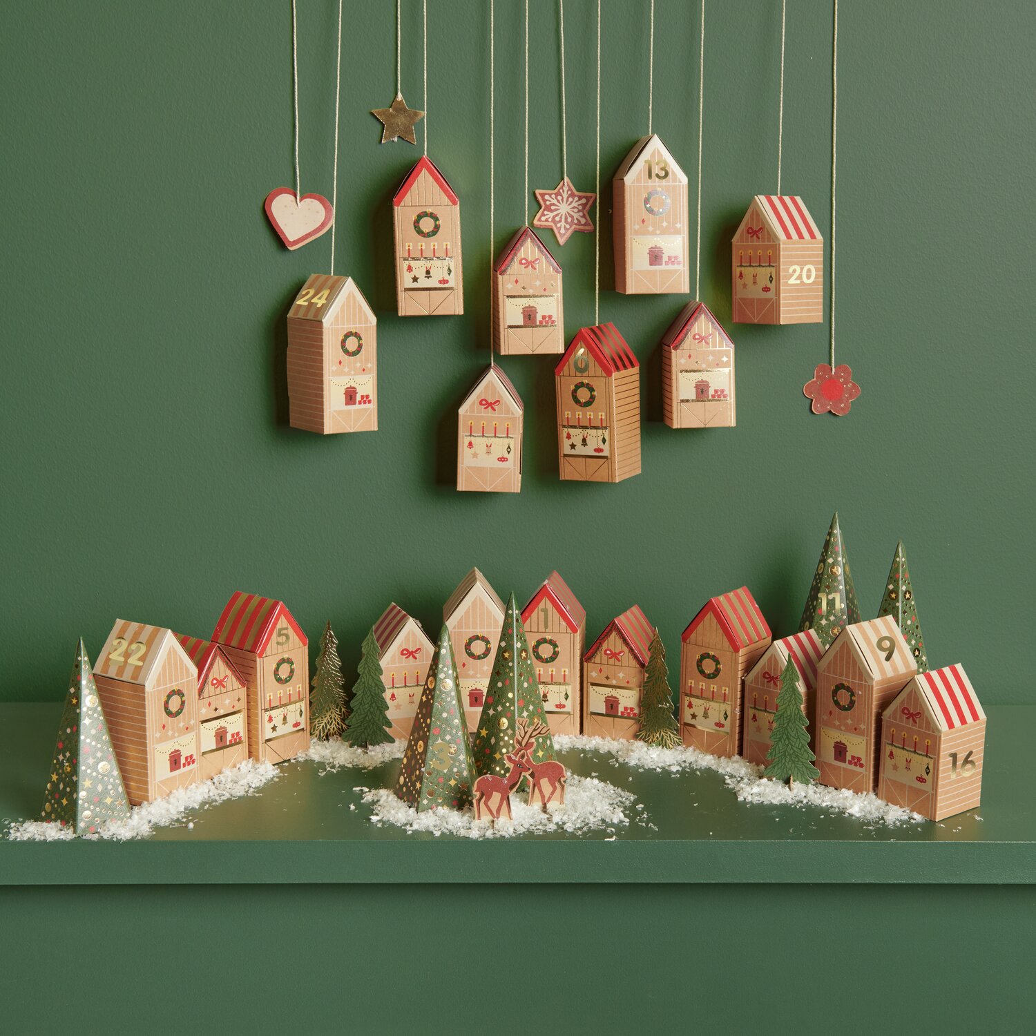 Adventskalender Bastelset: Kreatives Set mit hängenden und stehenden Häuschen in Rot und Naturtönen, dekoriert mit Schneeflocken und Tannenbäumen.