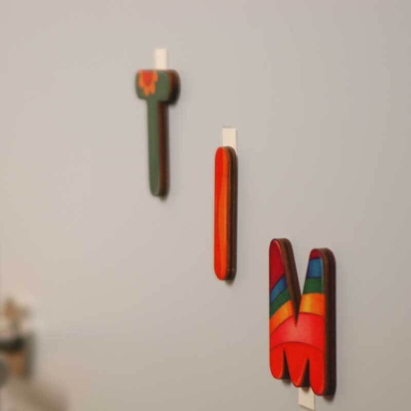 Powerstrips small 14 Stück: Bunte Buchstaben hängen an der Wand mit weißen tesa Powerstrips.